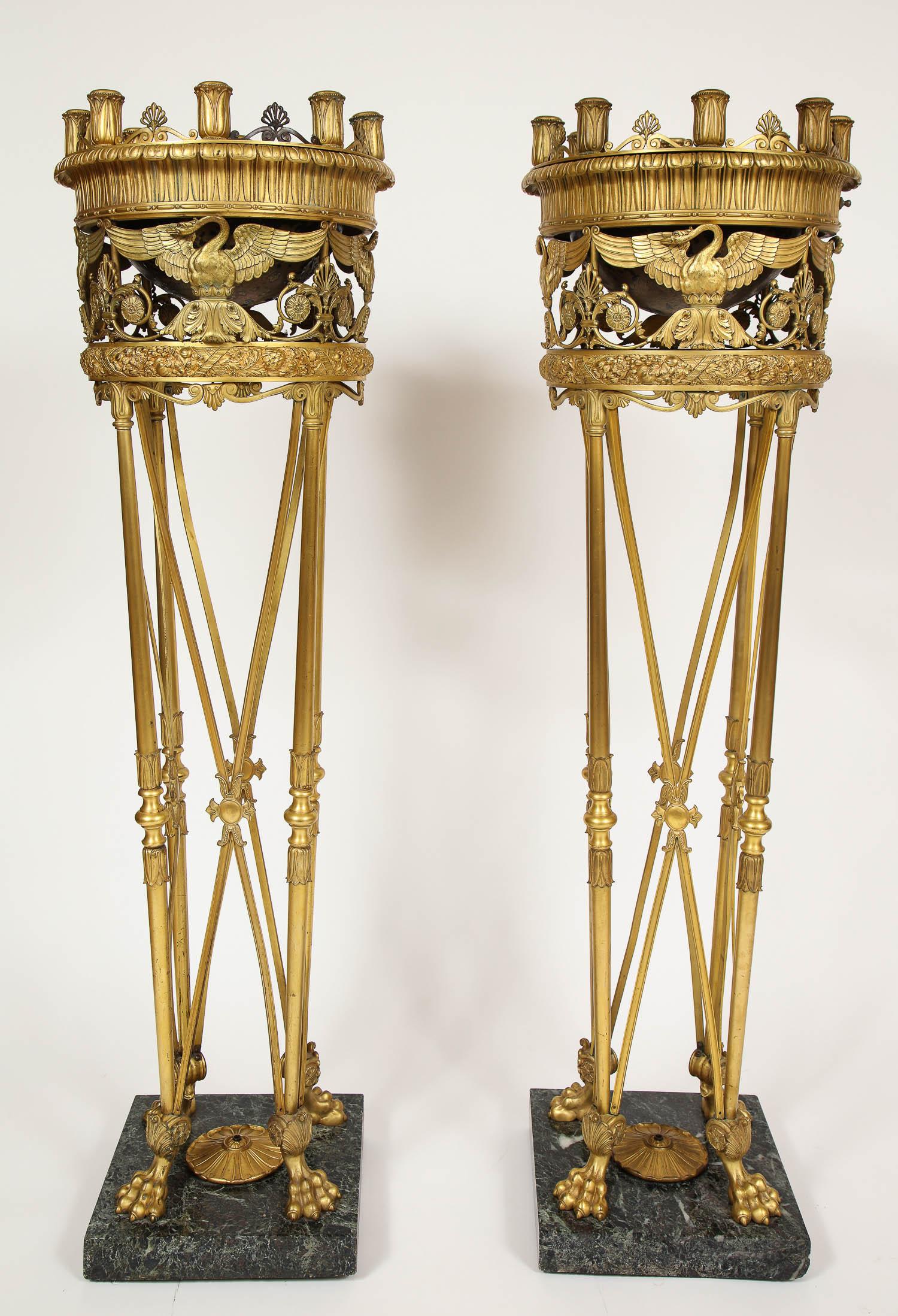 Une paire inhabituelle et rare de torchères/centres de table à huit lumières en bronze doré et marbre vert, attribuée à E. F. Caldwell and Co New York. De style Empire, la frise circulaire ajourée est décorée de cygnes et d'hymnes au-dessus d'une