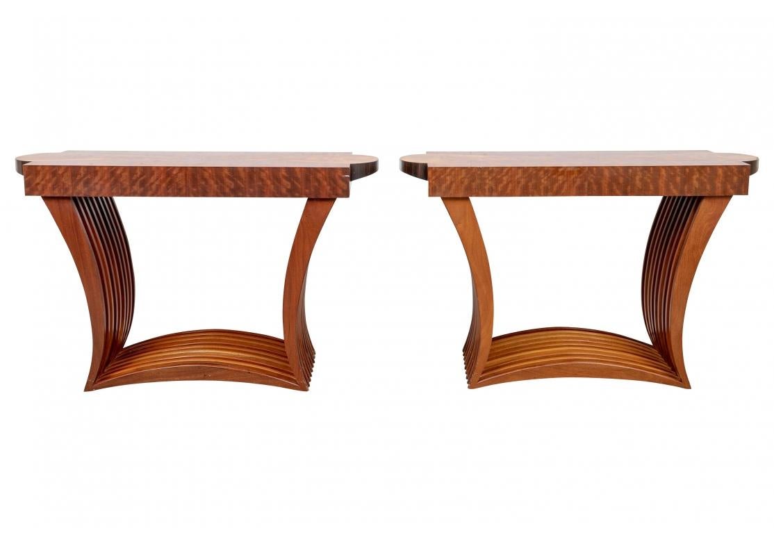 A Pair of meticulously crafted shaped rectangular pair of consoles in mixed woods. The tops in Stained Birch with inset center panels with curved ends and contrasting wood aprons on the short ends. Raised on square slatted curved supports mounted on