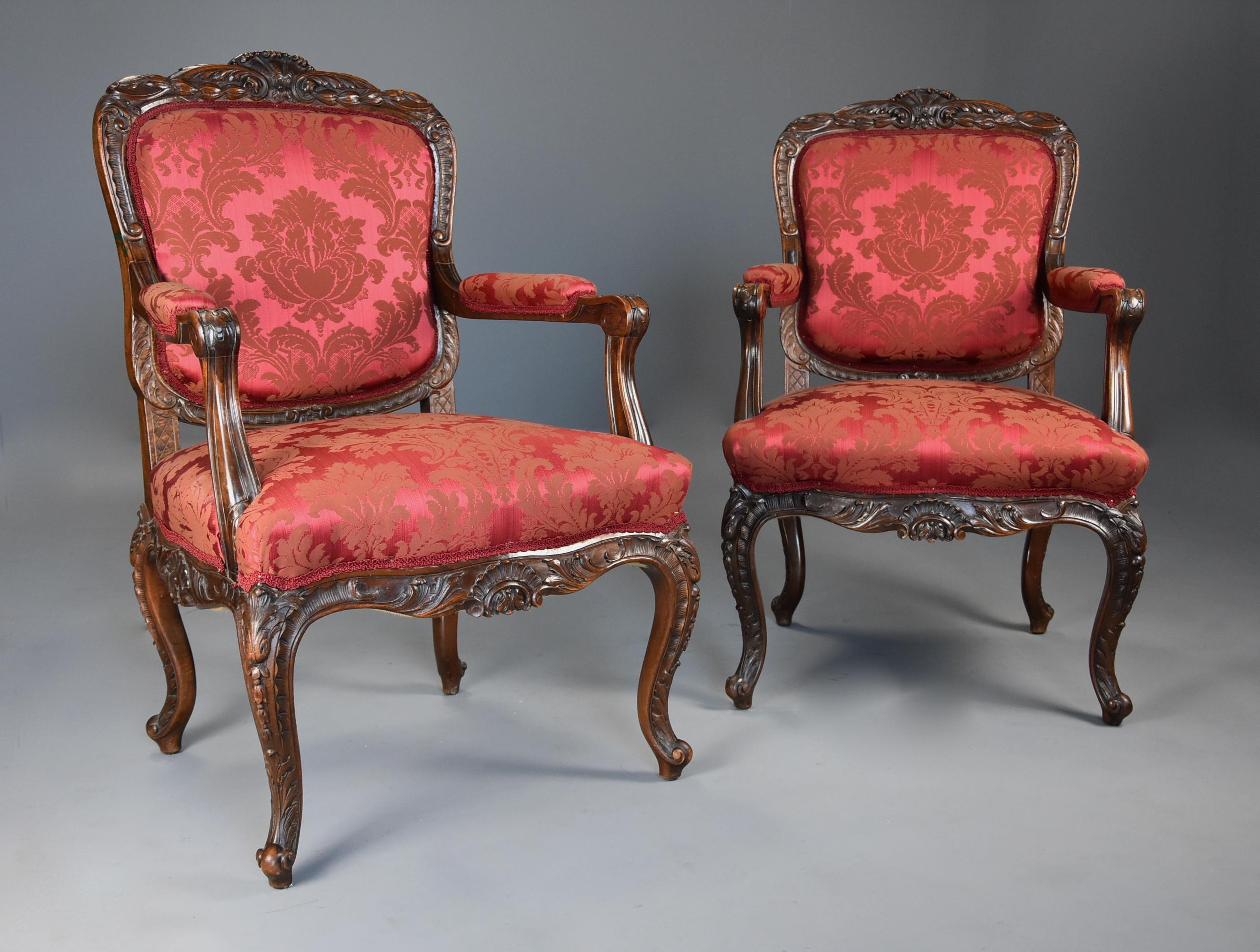 A pair of fine quality French 19th century, circa 1870 walnut fauteuils or open armchairs finished in a red damask fabric.

This pair of chairs consist of a finely carved top rail with central carved shell decoration with foliate and harebell