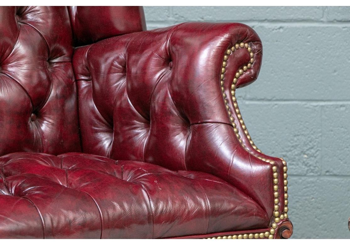 A very well made and comfortable pair of Glazed Leather Wing Chairs.   With tufted front, inside the rolled arms and seat, plain leather back and sides, all in a glazed finish. With nail head trim. Raised on front legs with carved knees and