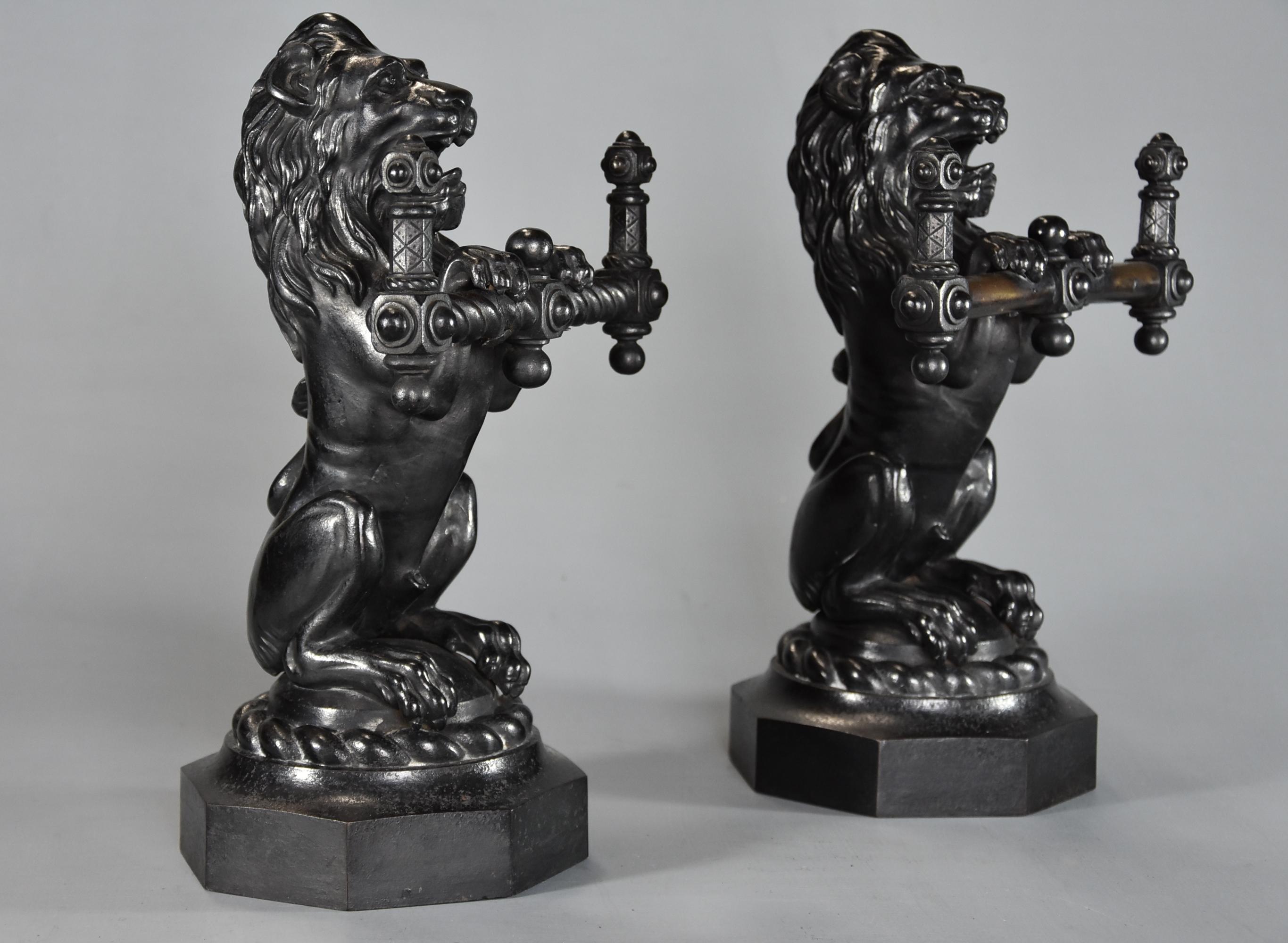 Pair of Fine quality late 19th century cast iron fire dogs in the form of lions.

This pair of finely cast fire dogs consist of a pair of lions seated on their hind legs with open mouths, one holding spiral twist support, the other holding plain