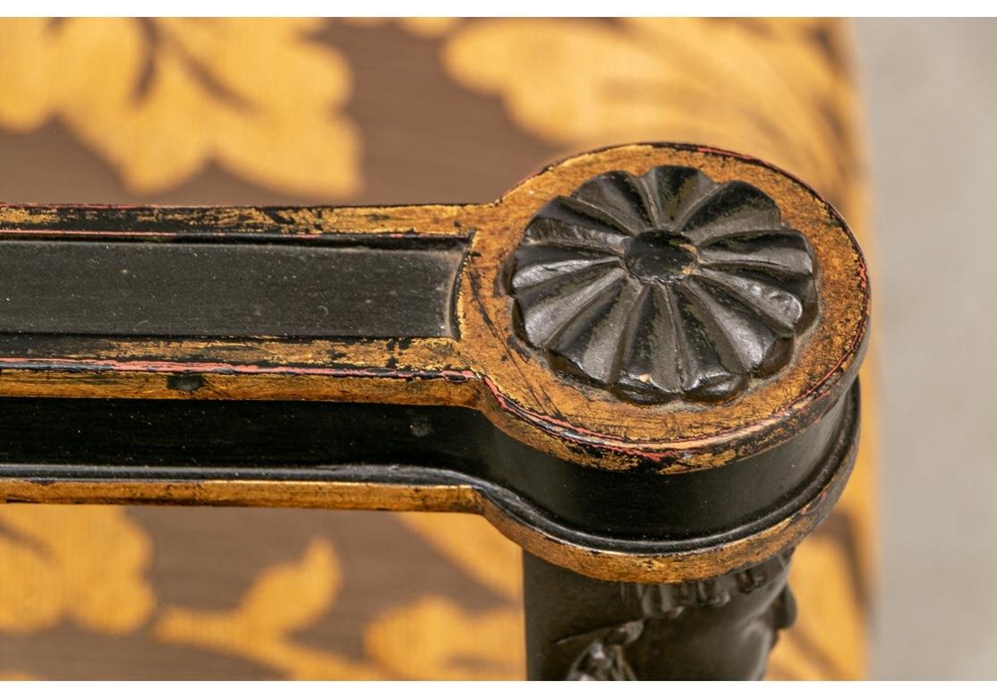 Ebonized frames with gilt details overall. The square backs with scrolled crest rails. The arms with carved rosettes on the ends over female beaded protomes on tops of the supports. Raised on square tapering legs with carved paw feet in front.