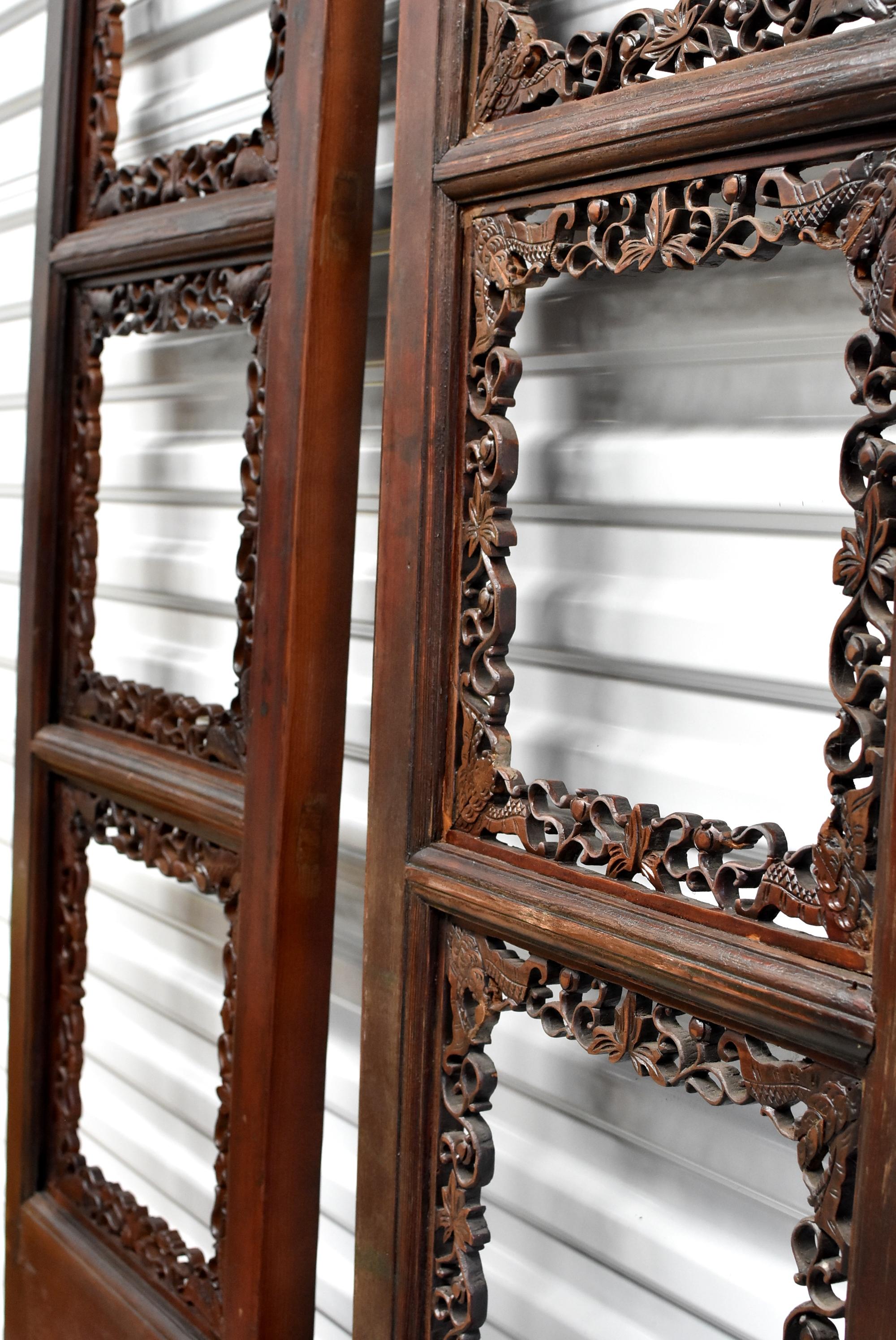 A pair of beautiful finely carved Chinese Antique screens. The main openwork features finely carved auspicious motifs such as butterflies, gourds and foliage. The bottom halves are solid panels with remnants of colors from before. Their mottled