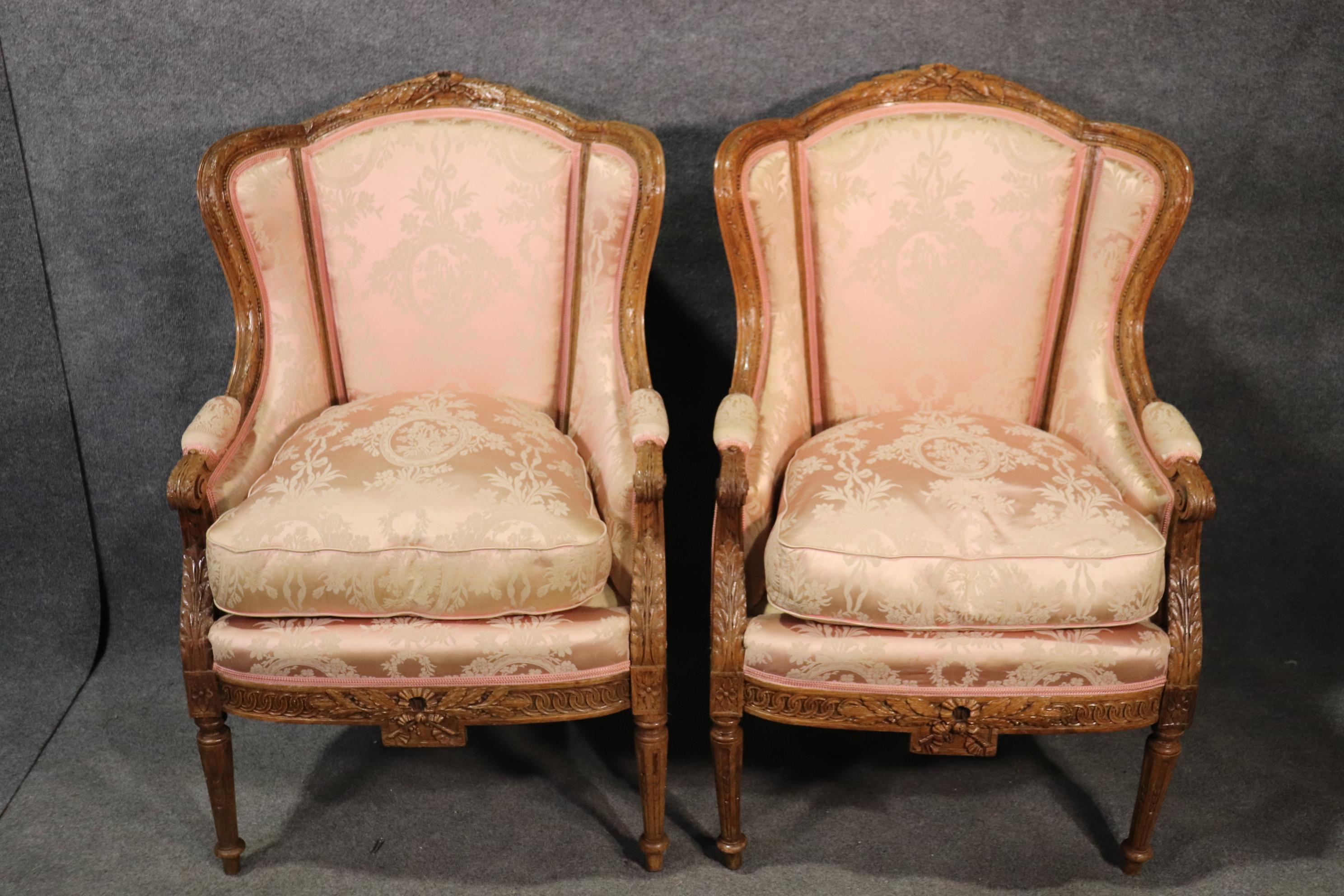 This is a special pair of formal carved oak wingback bergère chairs. Beautifully carved in a medium oak these chairs are in good condition with nice upholstery that while not perfect, is still very good and usable. The frames are just beautiful. The