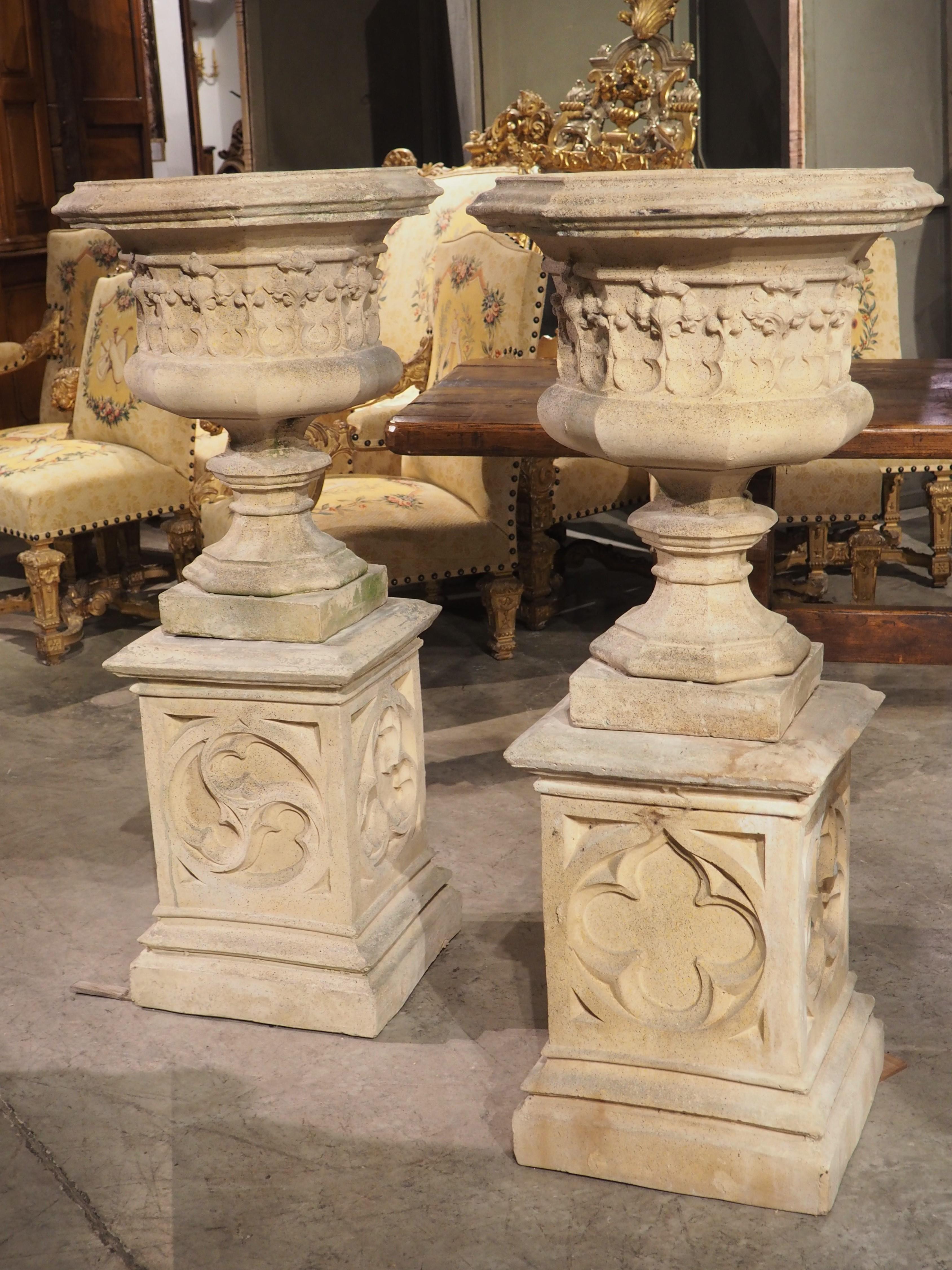 These cast French vases with matching pedestals have some exquisite Gothic motifs. Both octagonal vases have several layers of molding along the 17 inch opening. The main body is adorned with finely detailed foliate tracery set between two half