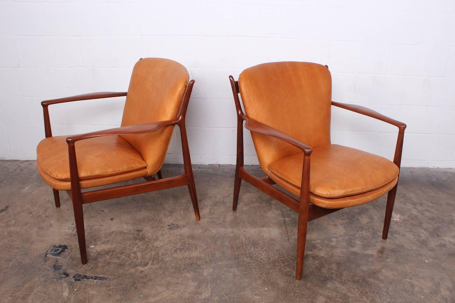 A pair of walnut delegate armchairs designed by Finn Juhl for Baker. Fully restored and upholstered in waxed leather.