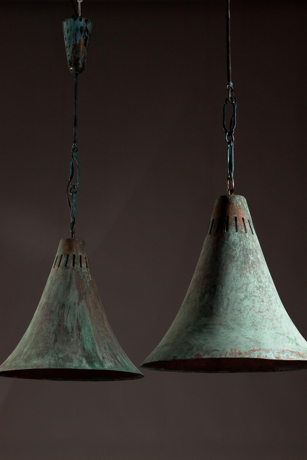 Introducing a pair of exquisite Finnish XL size industrial pendants from the 1930/40's era. These stunning lamps are made from oxidized copper, giving them the perfect patina for a rustic, industrial feel. Their adjustable height feature allows you