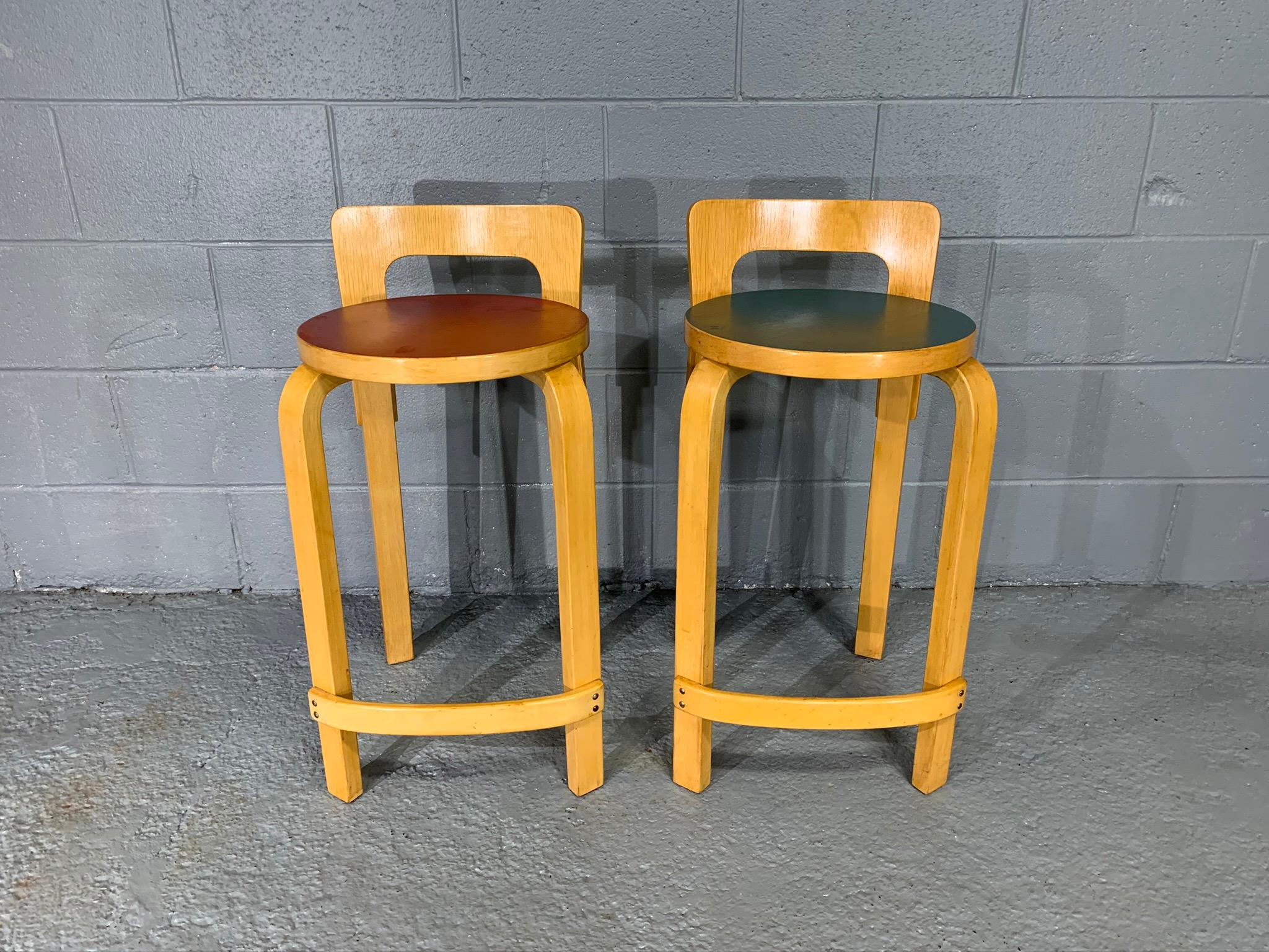 Pair of Finnish Mid-Century Modern Alvar Aalto bar stools / high chair for Artek, model K65. Made of birch with red and green linoleum in seating.