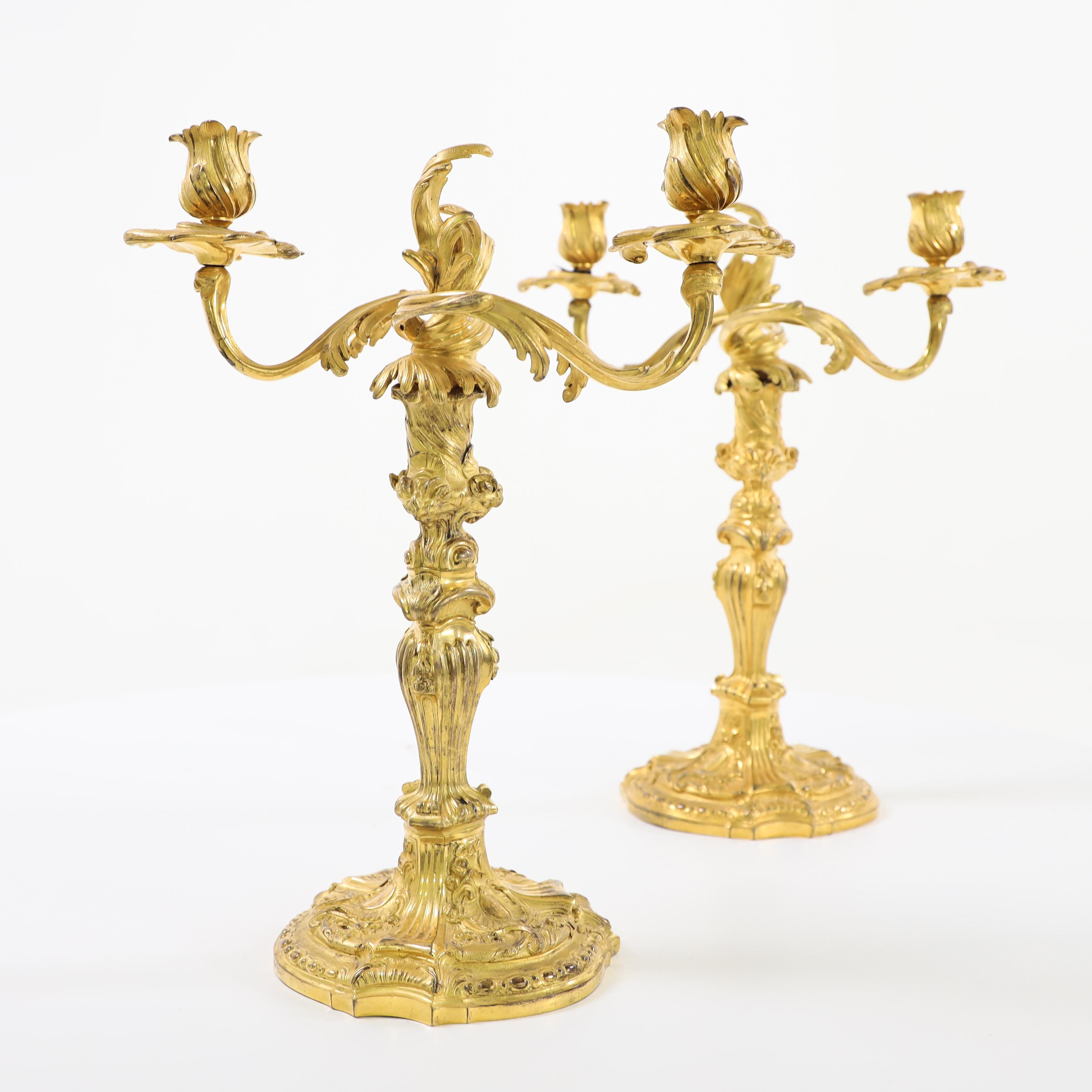 Pair of fire gilded candlesticks with balustered shafts with rocaille decor and removable leaf-shaped top with two spouts each.