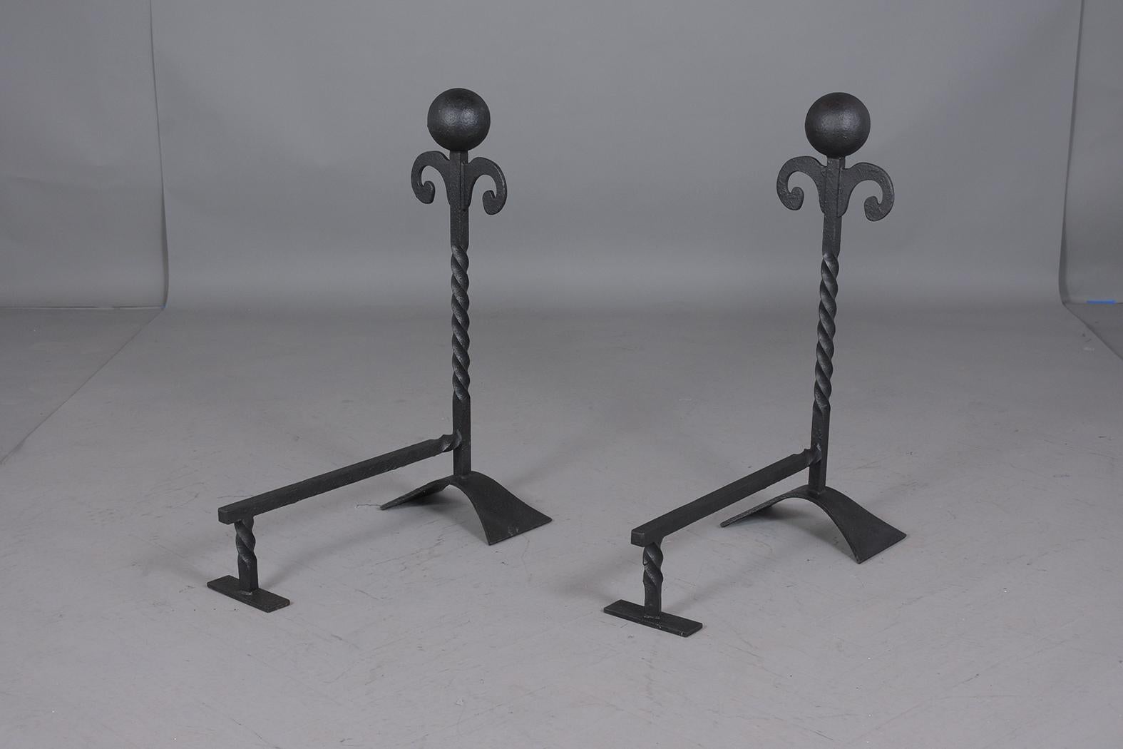 A set of baroque-style fireplace chenets hand forged out of iron that has been painted in black color with a polished patina finish. These large chenets feature an elegant baroque design and are ready to be used for years to come.