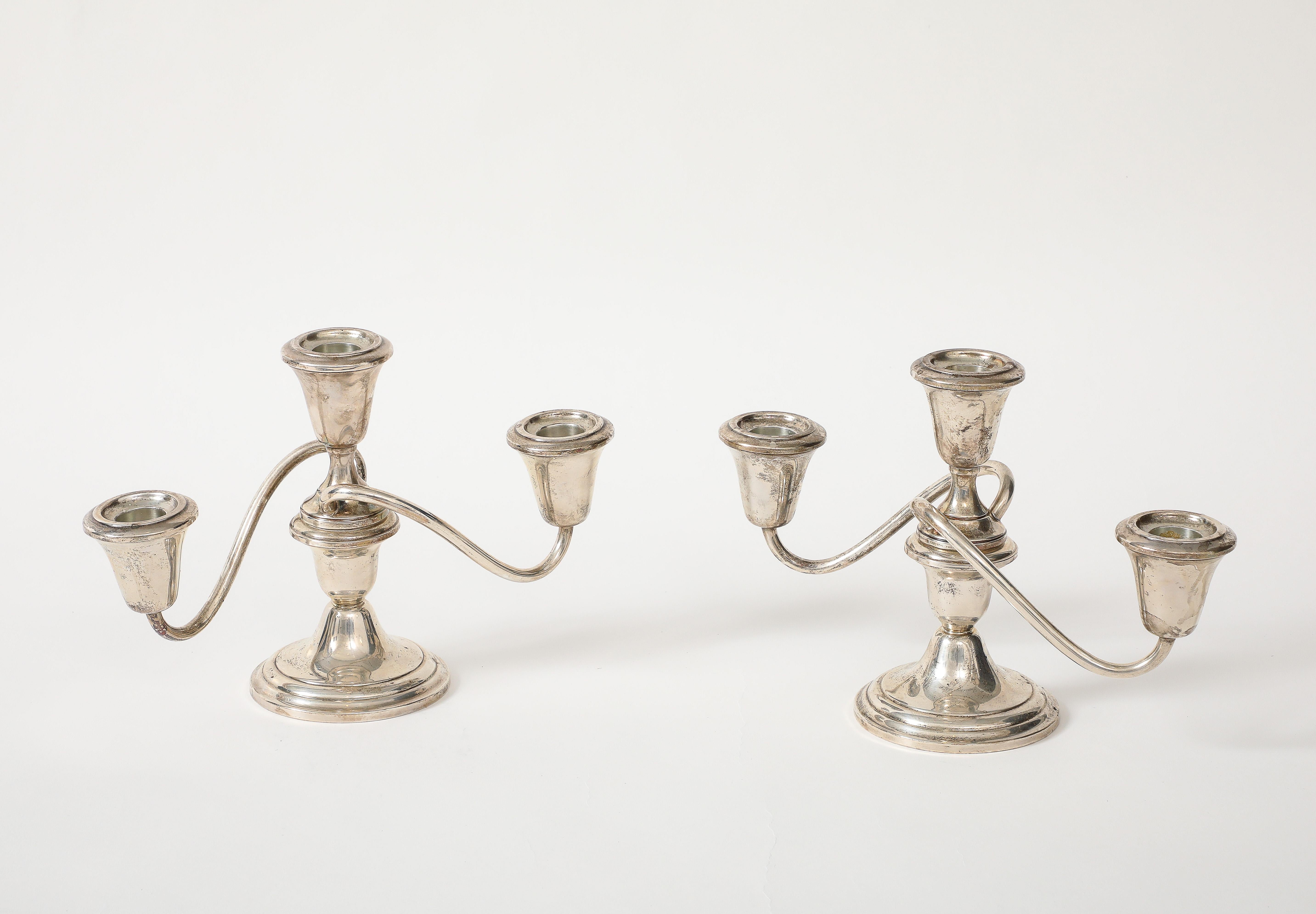 Coppia di eleganti candelabri Hollywood Regency in sterling, ciascuno dotato di 3 portacandele su bracci sinuosi e una colonna centrale tornita. Stampato sul fondo