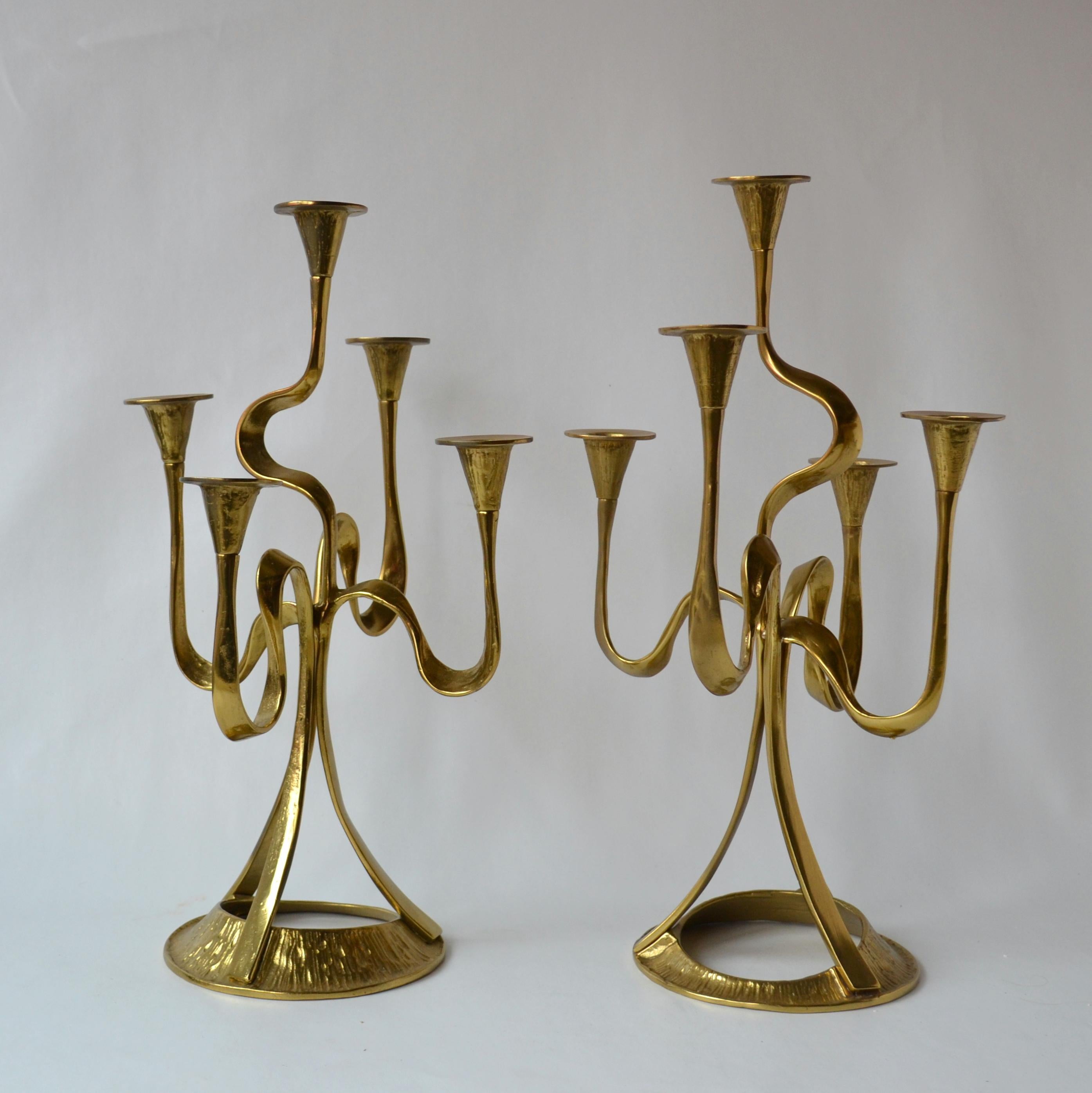 Two organic shaped ribbon form five-arm candelabra's cast in brass, swirling irregular arms link together on a sculptural round base evoking the Art Nouveau style. The candleholders have an irregular textural surface that catches the light. These