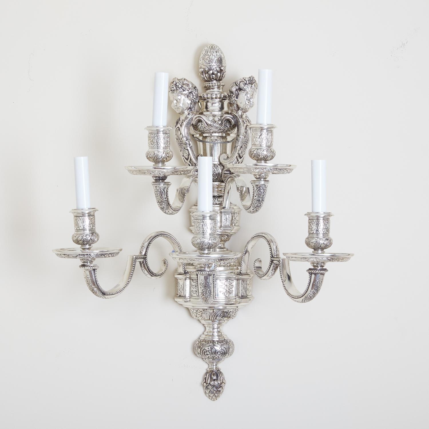 A pair of exquisite, documented Caldwell wall sconces. Each featuring five lights, these sconces are beautifully crafted, with silver nickel plated frames featuring vase shaped backplates. These light fixtures also feature two tiers of candle arms,