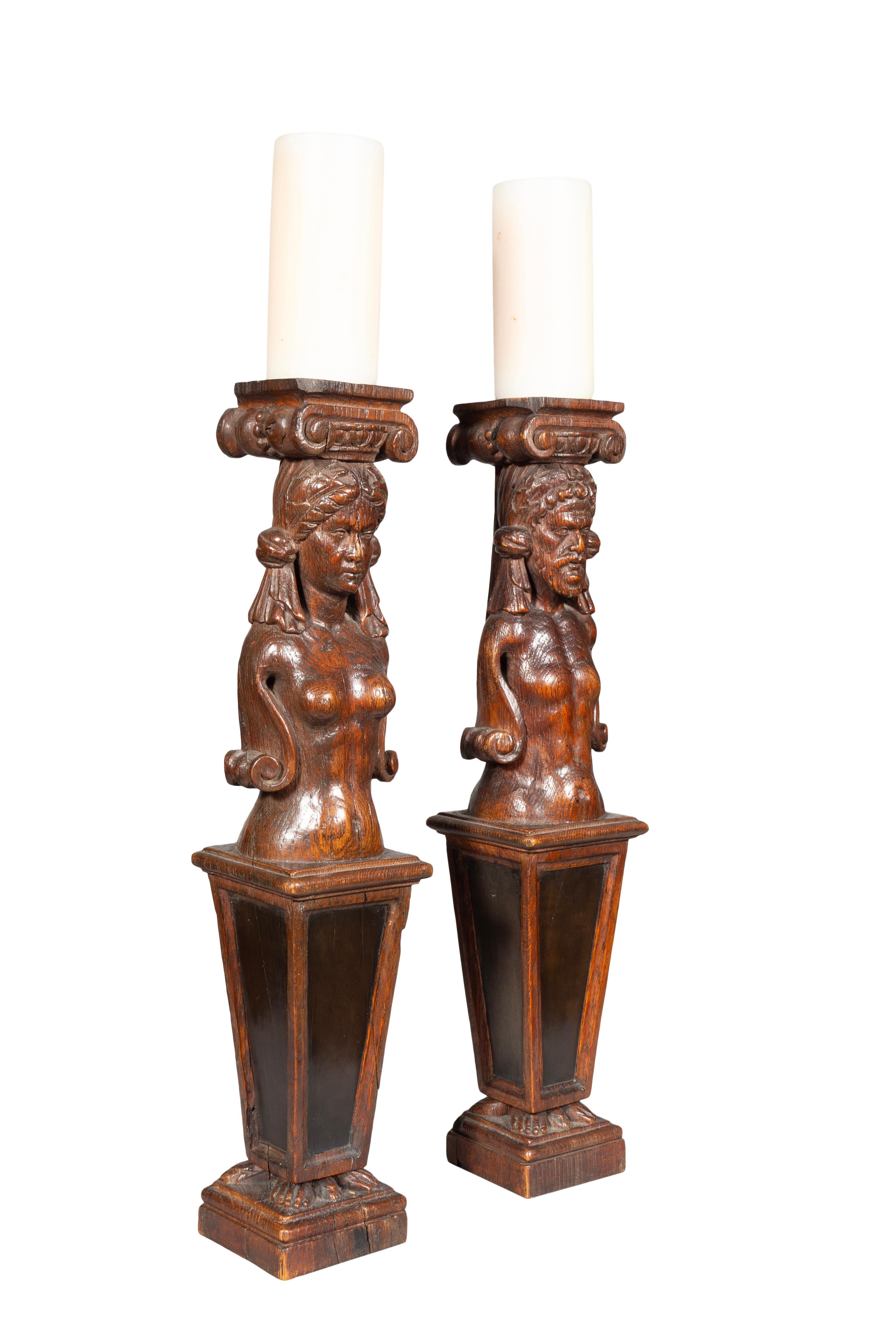 Likely from a piece of furniture. Featuring a well carved male and female over an ebony panel. Now used as candlesticks.