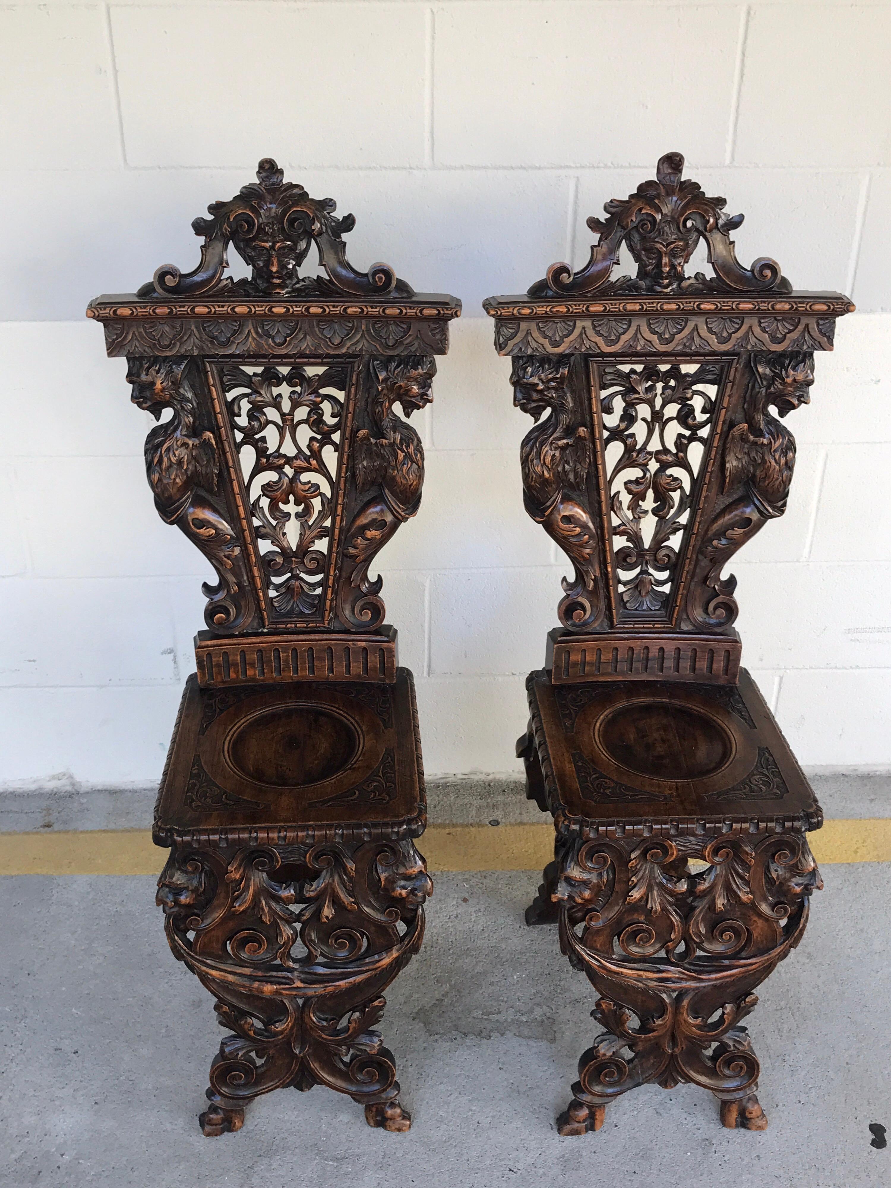 Pair of Flemish carved walnut fireside chairs, each one of diminutive proportions and profusely hand carved in the Renaissance style.