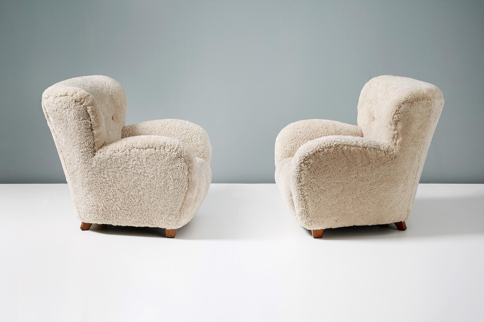 A pair of vintage lounge chairs produced in Denmark in the 1940s-1950s and attributed to designer Flemming Lassen. The legs are made from stained elm wood and the chairs have reupholstered in luxurious 'Moonlight' color shearling from New