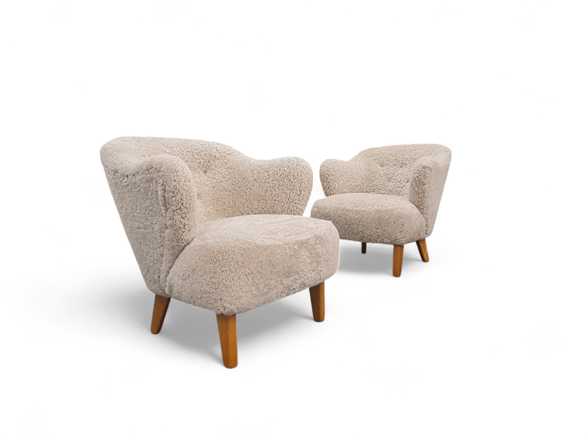 Una bella coppia di poltrone Ingeborg dell'architetto danese Flemming Lassen in pelle di pecora naturale beige liscia. 

I braccioli sinuosi e lo schienale leggermente arrotondato con bottoni conferiscono alle sedie una forma moderna e distinta.