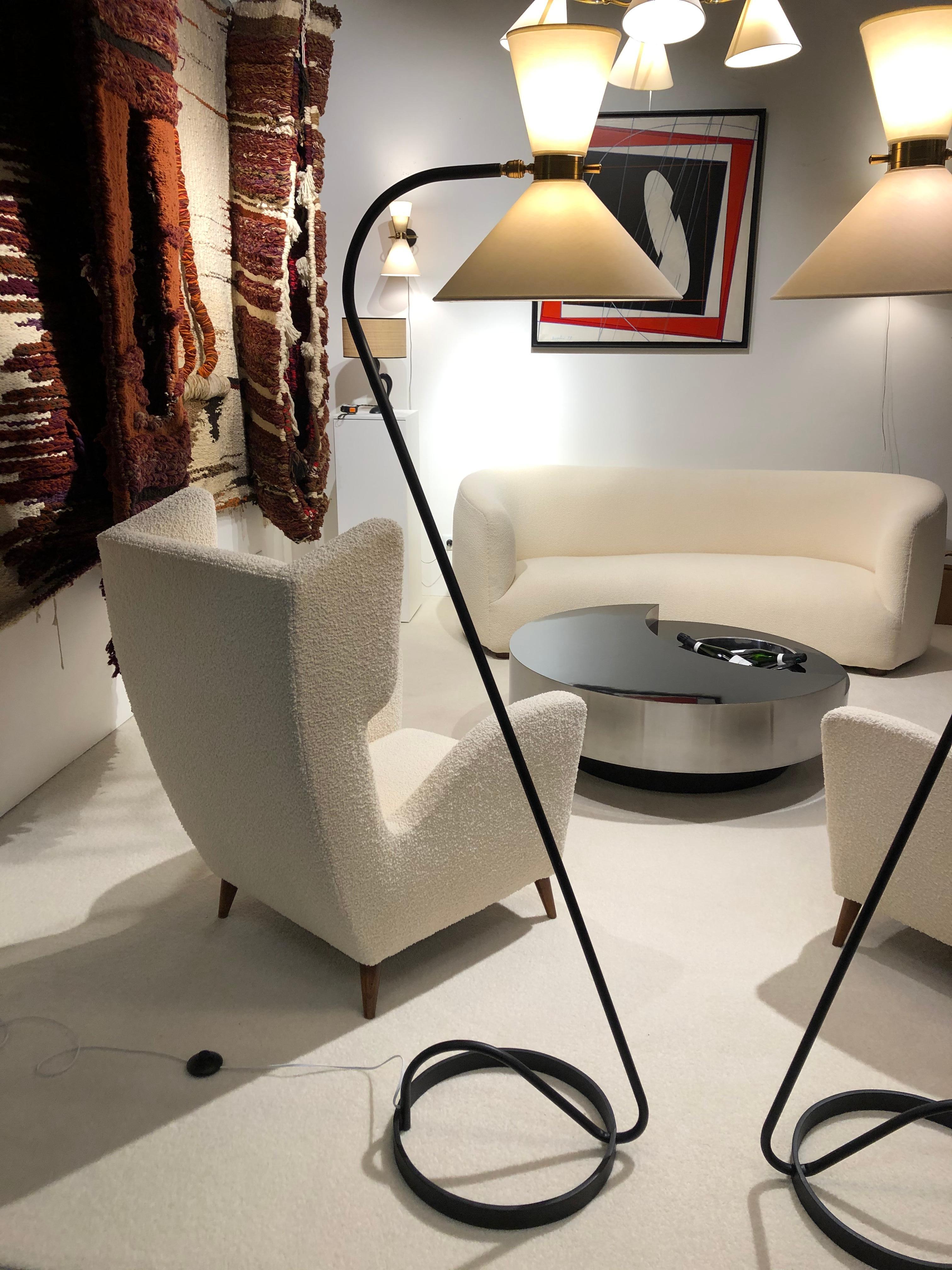 Pair of floor lamp in black lacquered metal and brass, composed of a circular base in black lacquered,
a brass ring articulated by a ball joint, receiving on both sides two conical lampshades diffusing light. A brass handle allows easy