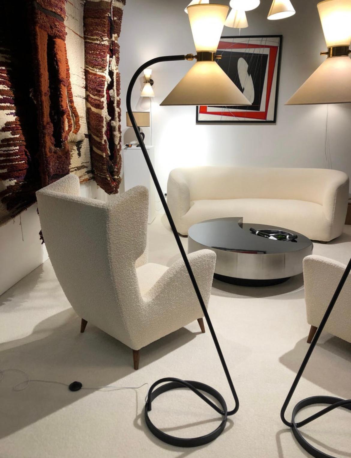 Pair of floor lamp in black lacquered metal and brass, composed of a circular base in black lacquered,
a brass ring articulated by a ball joint, receiving on both sides two conical lampshades diffusing light. A brass handle allows easy