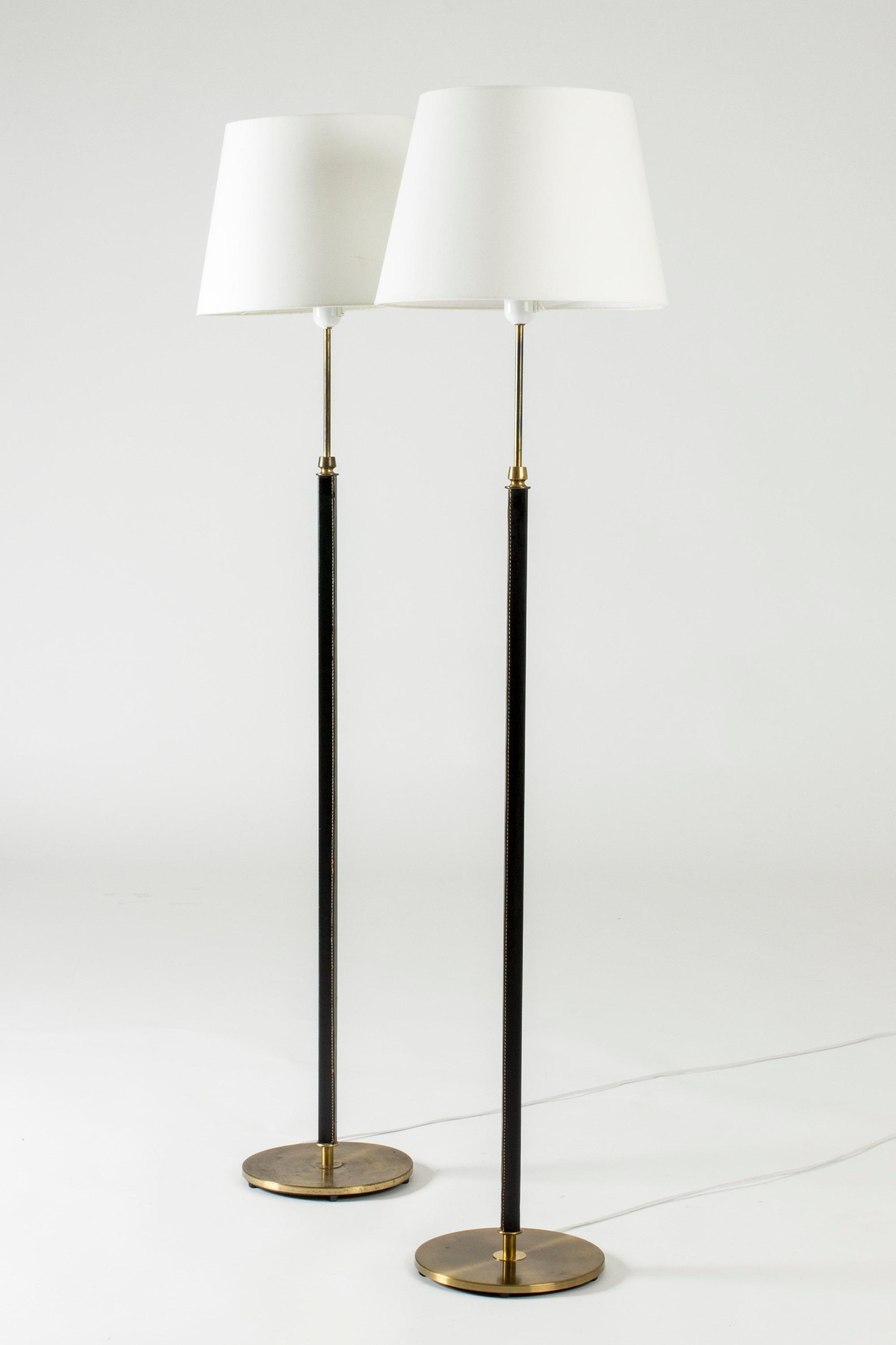 Pair of cool floor lamps from Falkenbergs Belysning, made from brass. Sleek square stems dressed with black leather.