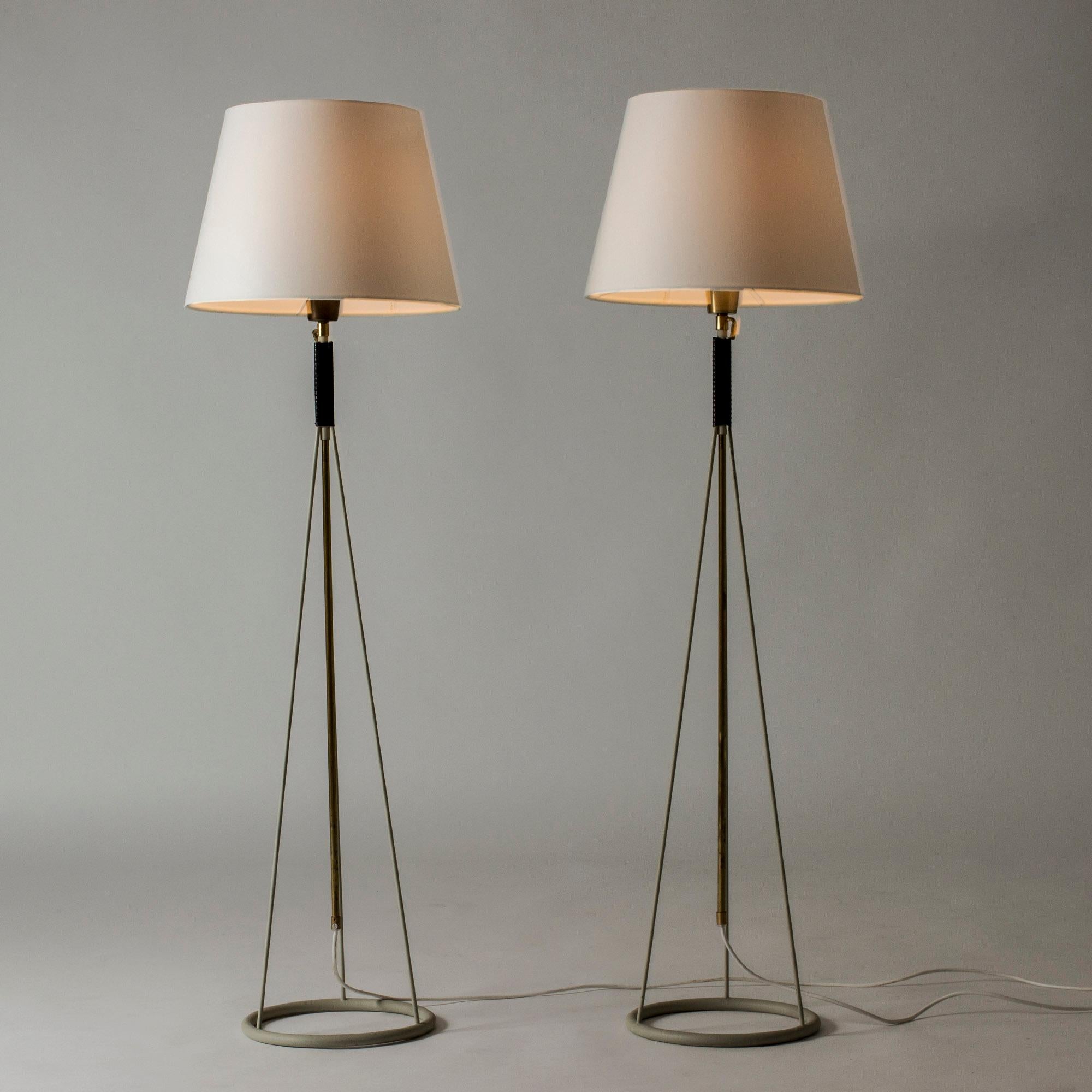 Pair of cool floor lamps from Luco, made from lacquered metal with brass details. Graphic look with circular bases. Adjustable height, 122-184 cm.