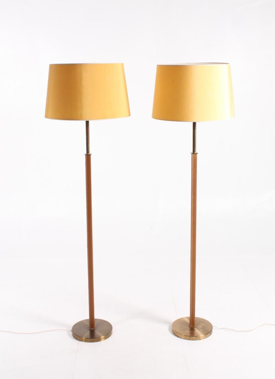 Pair of floor lamps covered in patinated leather on a round brass base. Designed and made in Sweden in the 1950s. Original condition.