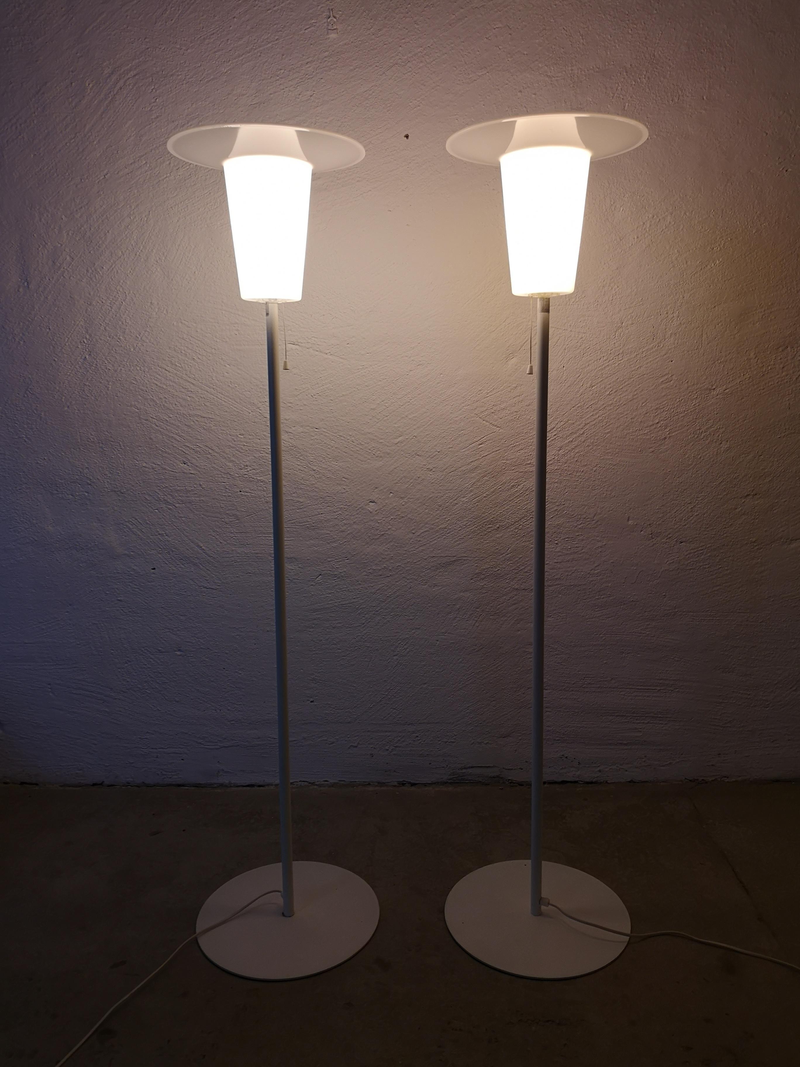 Two floor lamps maufacutred in sweden and Luxus. They are made in white with an iron cast base. The uplight shades are in acrylic. Its possible to put at shade on top of the plastic shades or just leave it as an uplight lamp. 

Nice vintage
