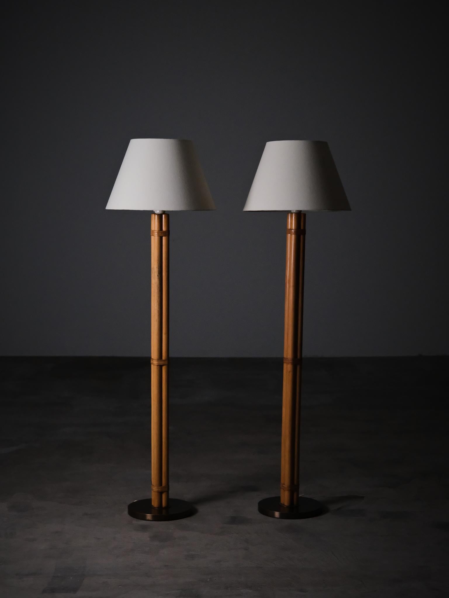 Paire de lampadaires conçus par Hans-Agne Agnes, modèle B105. 
Exécuté en bois façonné pour ressembler à du bambou, avec des détails en cuir et des bases en laiton. Produites en Suède dans les années 1960, ces lampes illustrent le sens raffiné des