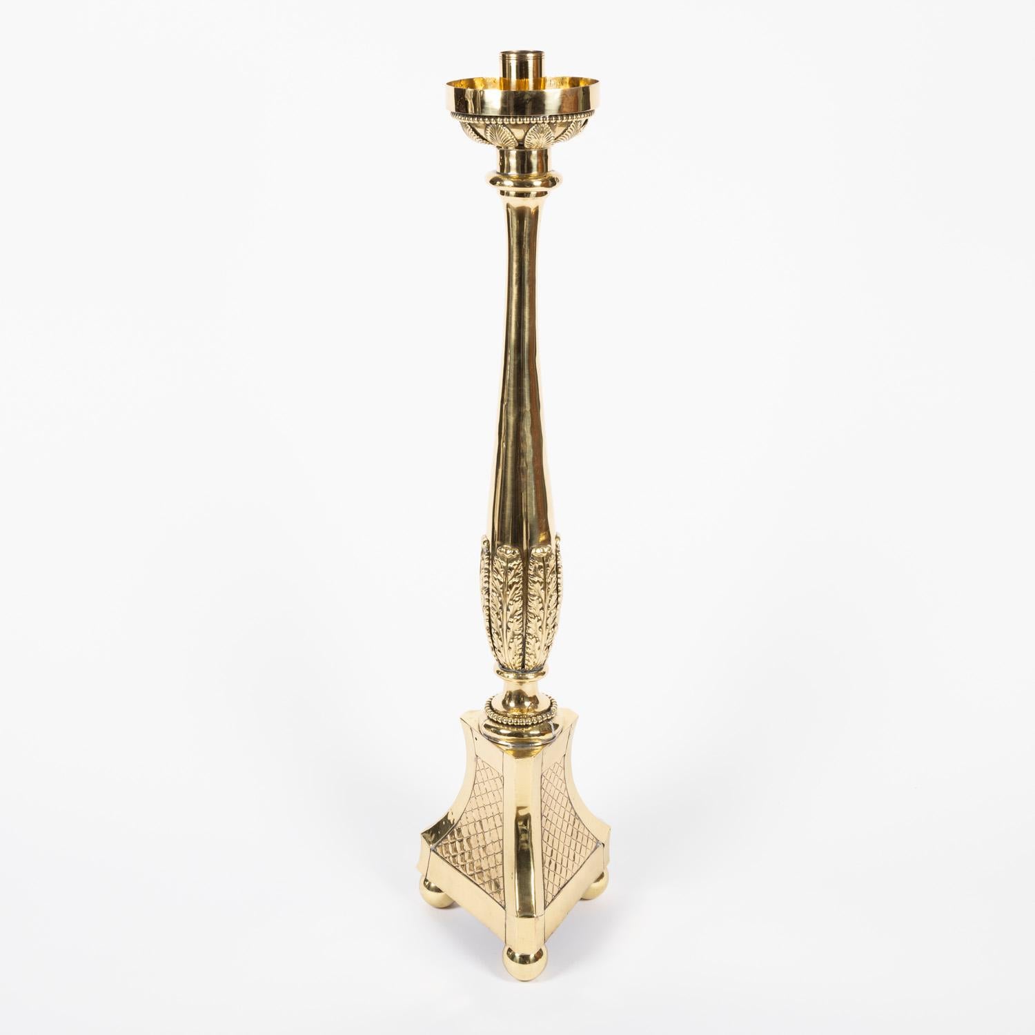 A pair of early 20th century floor standing brass candelabra.

The tray and stem of each candelabra is decorated with leaves, triform base, mounted on ball feet.

for use with candles.