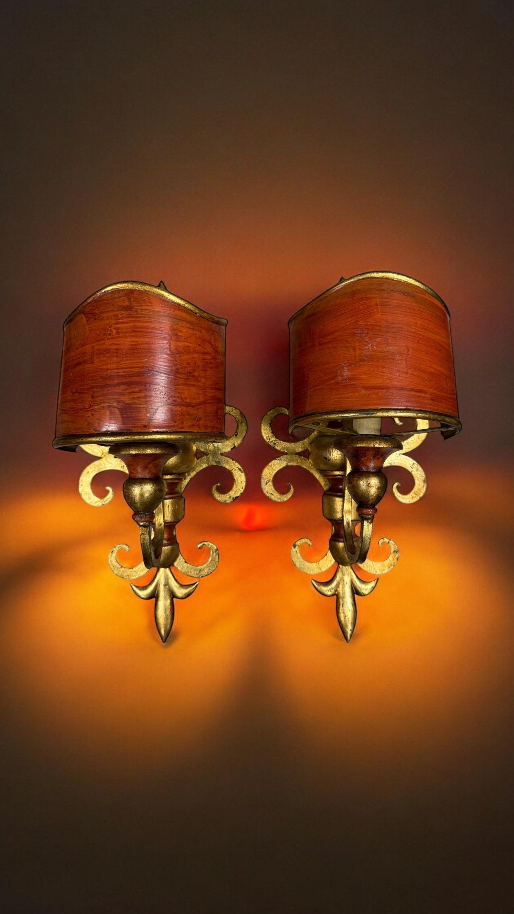 A pair Hollywood Regency midcentury gilt floral tole sconces in the form of French Lily, each fixture requires one European E14 candelabra bulb, up to 60 watts. The wall lights have a beautiful patina and give each room an eclectic statement. The