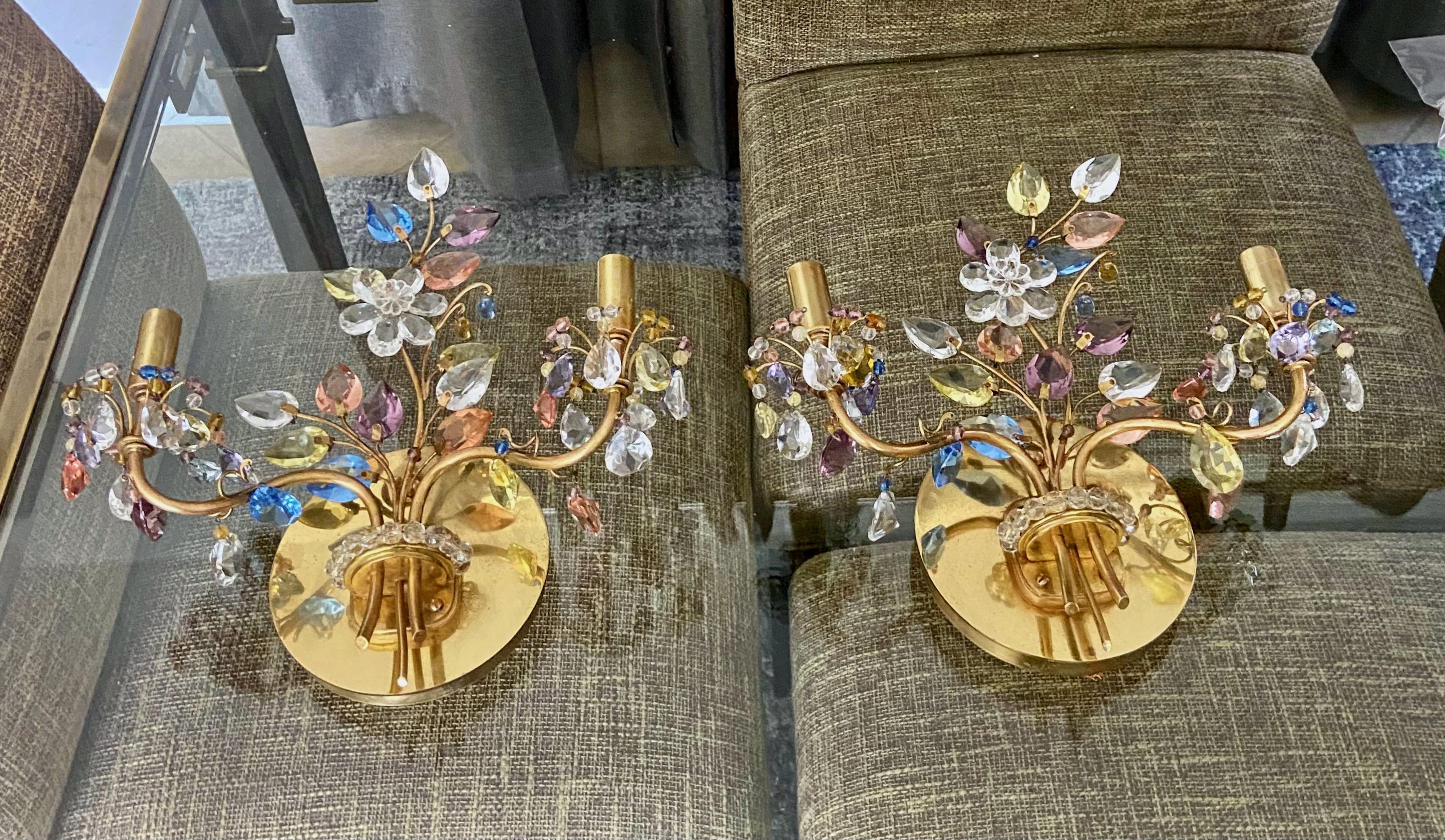 Coppia di applique a due luci disegnate da Oswald Haerdtl per J. & L. Lobmeyr. La struttura in ottone massiccio è saldata e lucidata per creare i delicati rami organici. Questi sono decorati con cristalli multicolore lucidati a mano che creano un