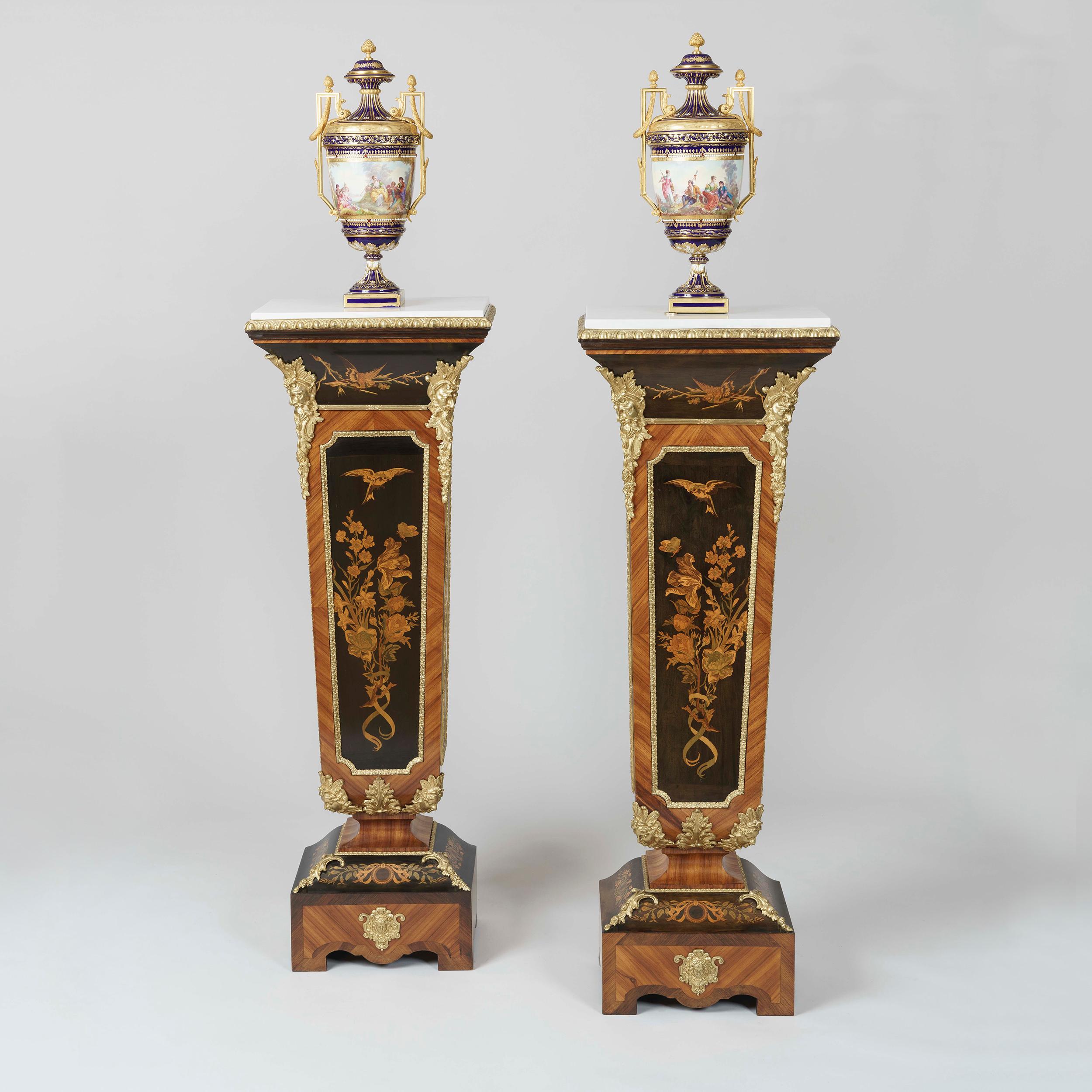 A pair of marquetry and Ormolu-mounted pedestals
Attributed to Joseph Cremer

Constructed from tulipwood, each pedestal of tapering rectangular form and dressed with ornamental gilt bronze mounts of female and bacchic masks, the front