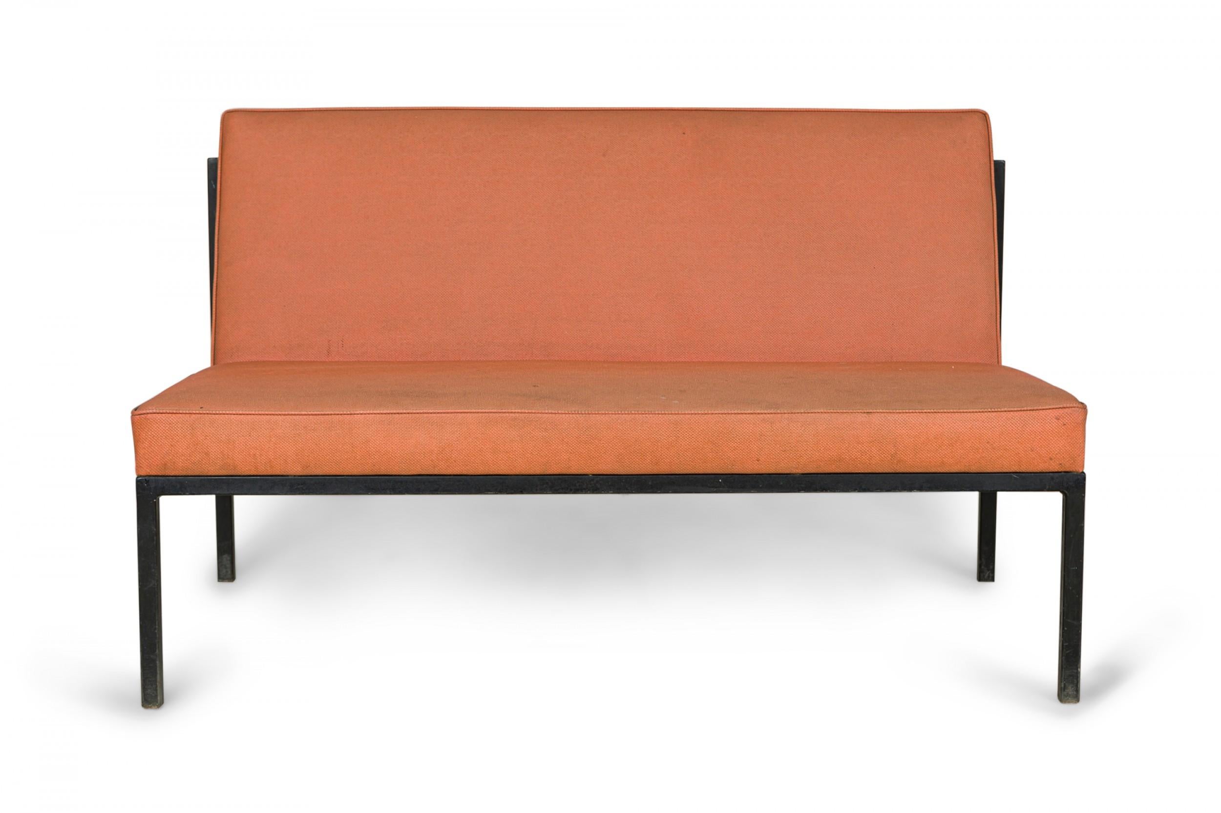 PAIR of American Mid-Century two-seat settees with peach color faintly textured upholstered seat and back cushions supported on black powder coated metal frames. (FLORENCE KNOLL / KNOLL INTERNATIONAL)(PRICED AS PAIR).
 