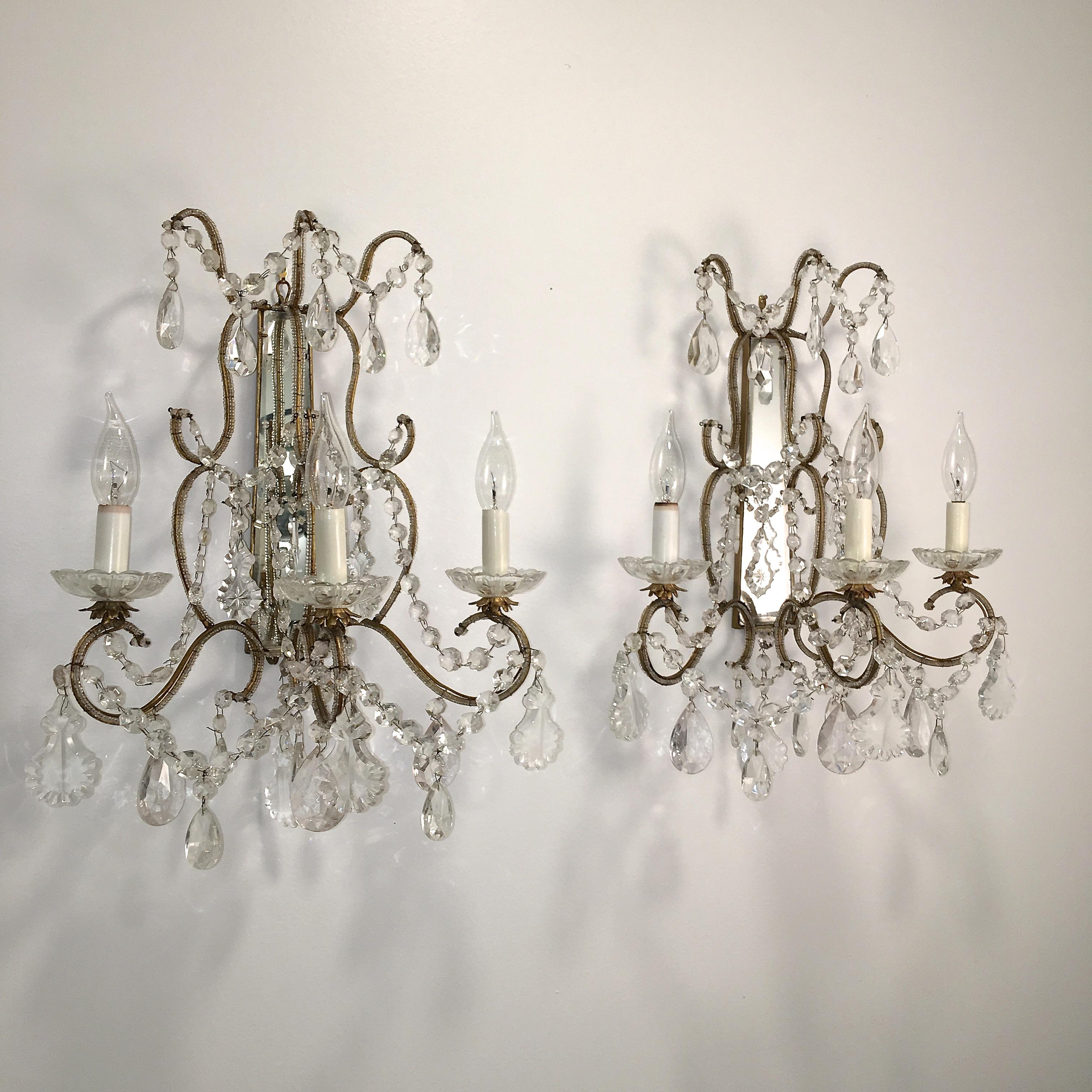 Pair of vintage Florentine beaded gilt metal and mirror framed three light sconces adorned with cut crystal garlands and drops. Wired for USA. Takes three candelabra size bulbs up to 250 watts per fixture.

Intended to be hard wired but can be