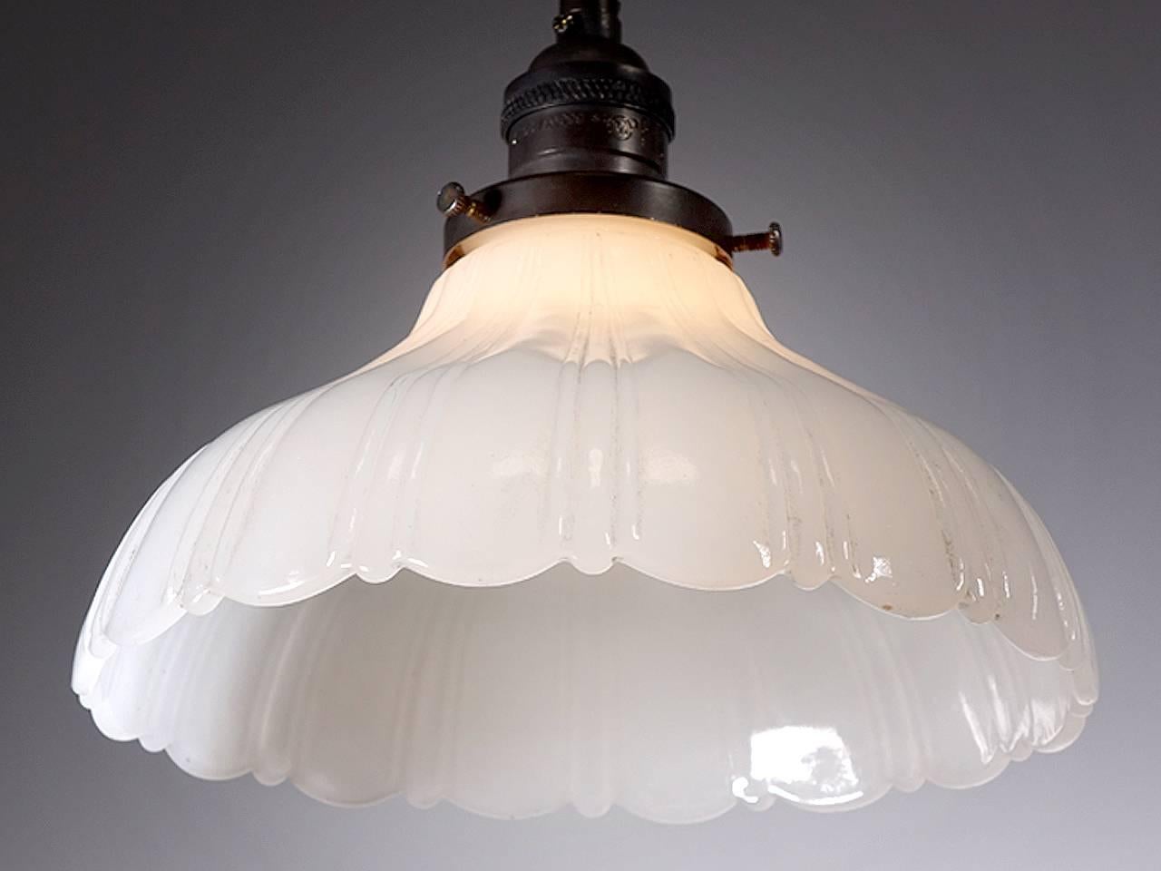 Softly curved bell shaped pendants are a Classic. They feel at home with any style decor. This example is an extra heavy thick-thin pattern in cast clam broth glass with a scalloped edge. The pattern has three thin ribs and one wide. The lamps are