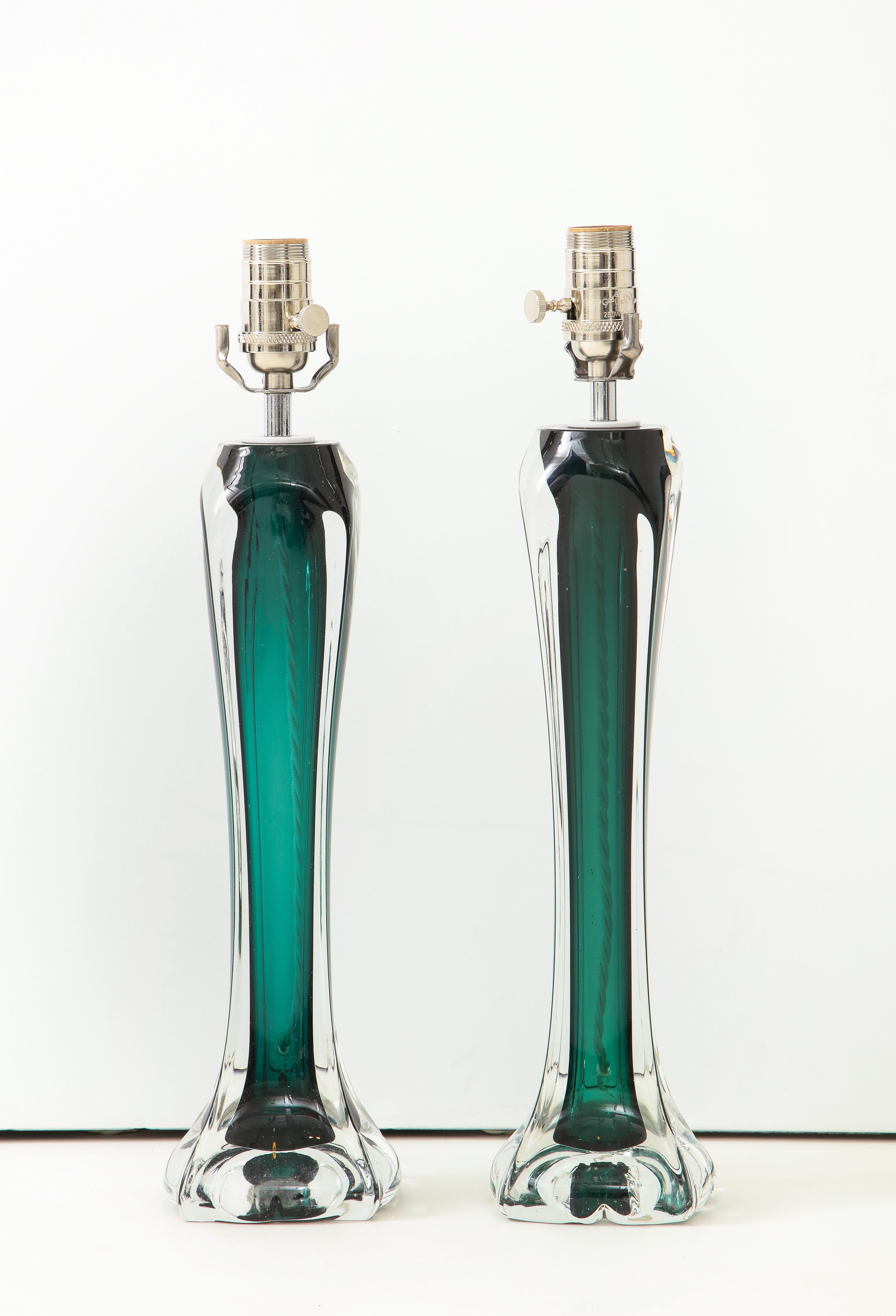 A pair of Flygsfors crystal lamps in a stunning emerald green. Sculptural in form, the narrow silhouette of the lamps tapers to a floral-like base. More than just lamps, these are works of art!