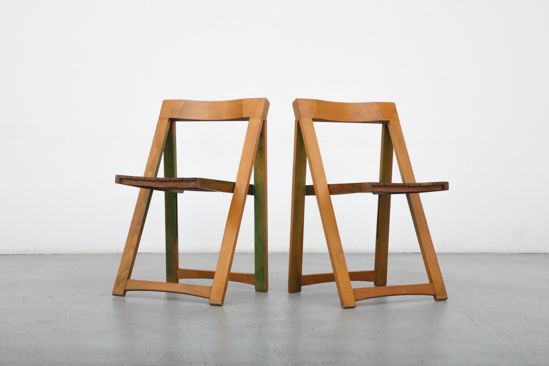 Coppia di sedie pieghevoli Aldo Jacober per Alberto Bazzani. Queste sedie presentano una macchia verde, un tempo scelta per il colore delle sedie, che si è consumata nel tempo. Ripiegate misurano 18 x 1,625 x 34,875 e sono in condizioni originali