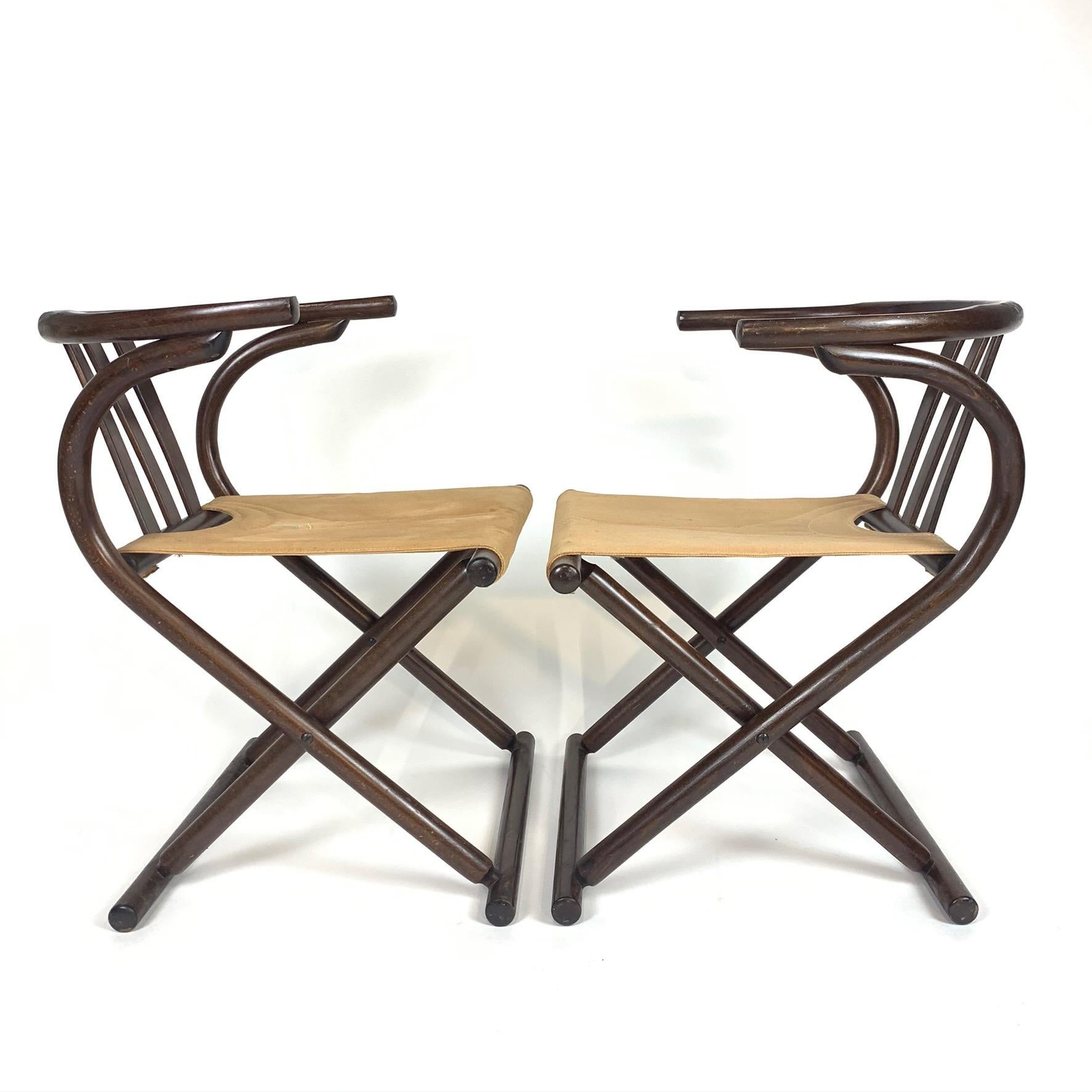 Unique pair of Thonet Mid-Century Modern bentwood chairs that fold. Dark bentwood frames with sturdy canvas seats with decorative stitching. Canvas on one chair has some discoloration as seen in photos.