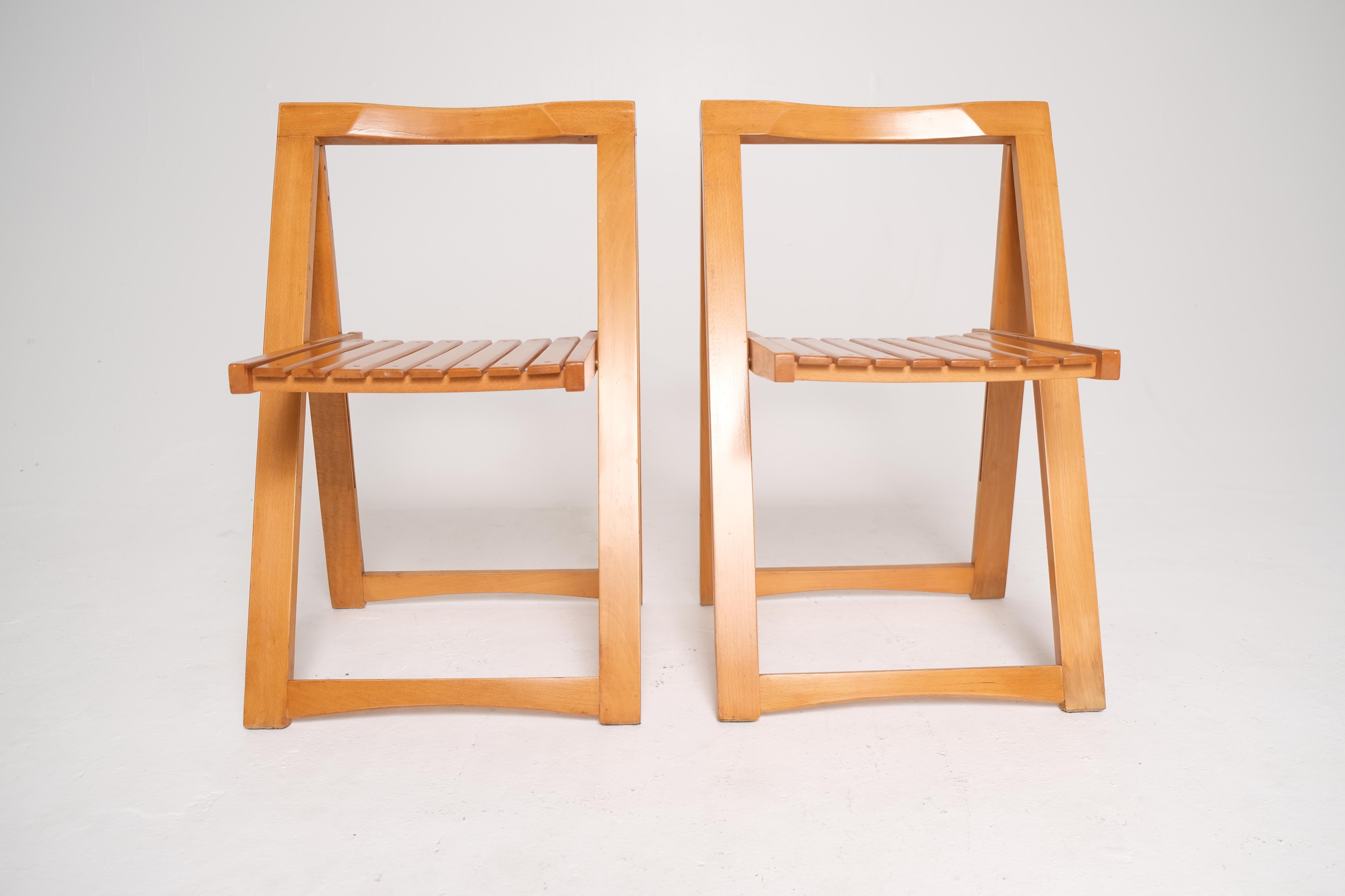A finely crafted pair of mid-century folding chairs designed by Aldo Jacober and produced by Alberto Bazzani in Italy, circa 1960s. Constructed from solid beechwood, each chair features a slatted seat and backrest, an angular A-frame silhouette, and