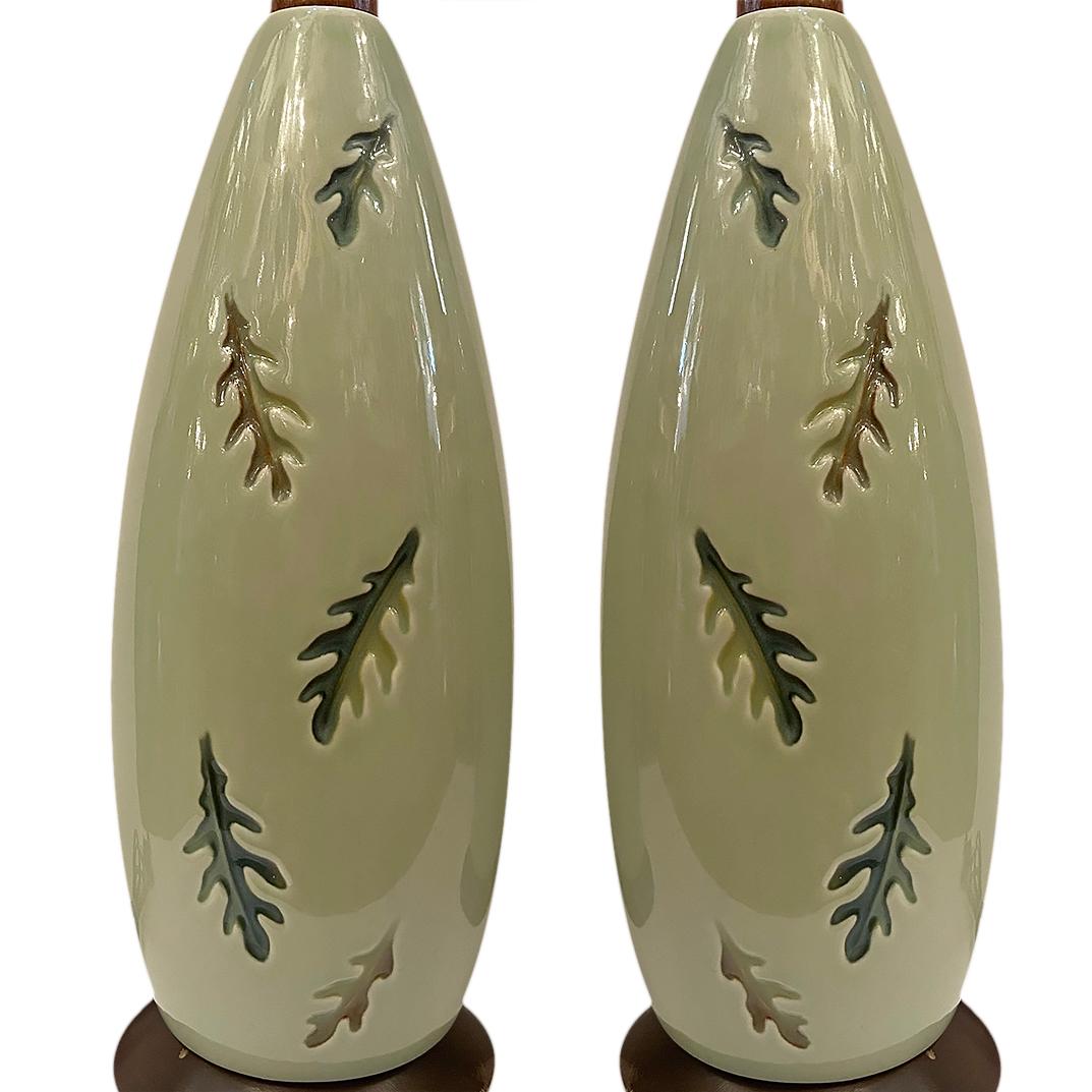 A pair of circa 1950's French celadon lamps with foliage motif on body.

Measurements:
Height of body: 17.25