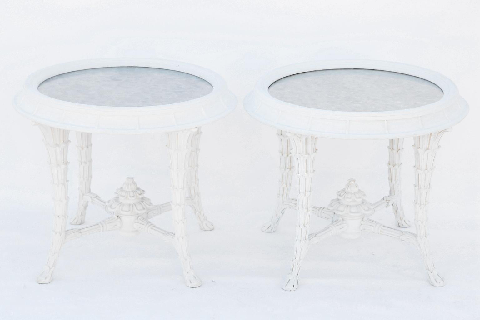 Pair of accent, or side tables, in the manner of Serge Roche, each round, molded top having a ribbed, concave frame, surrounding distressed mirror, raised on foliate-carved, tapering, splayed legs, joined by X-stretcher, and finished with a finial.