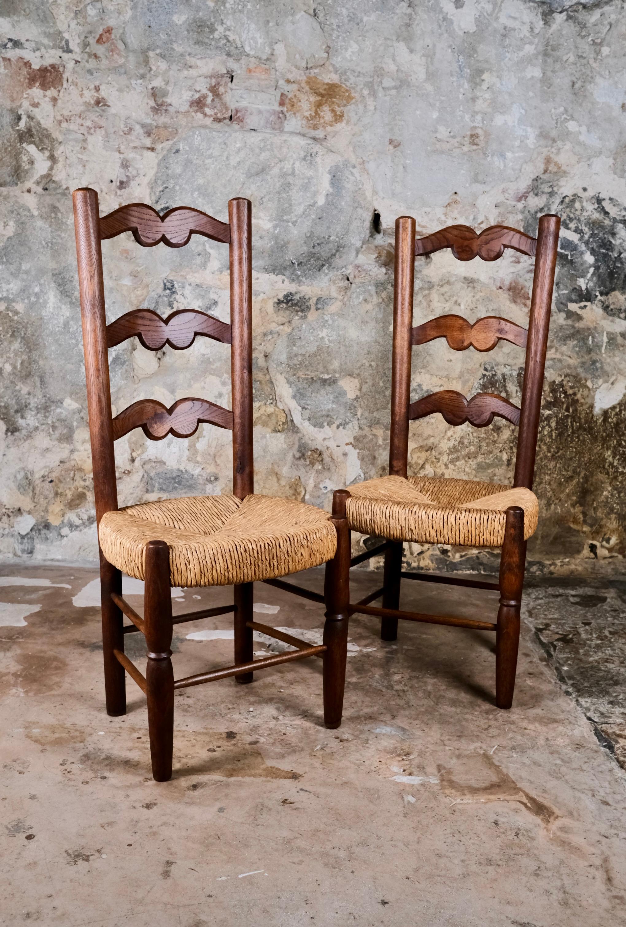 Bella coppia di sedie in paglia e quercia intagliata, arte popolare francese della metà del XX secolo. 
Proporzioni molto eleganti con uno schienale sottile e sedili spessi. Altezza della seduta per adulti.
In ottime condizioni generali.
