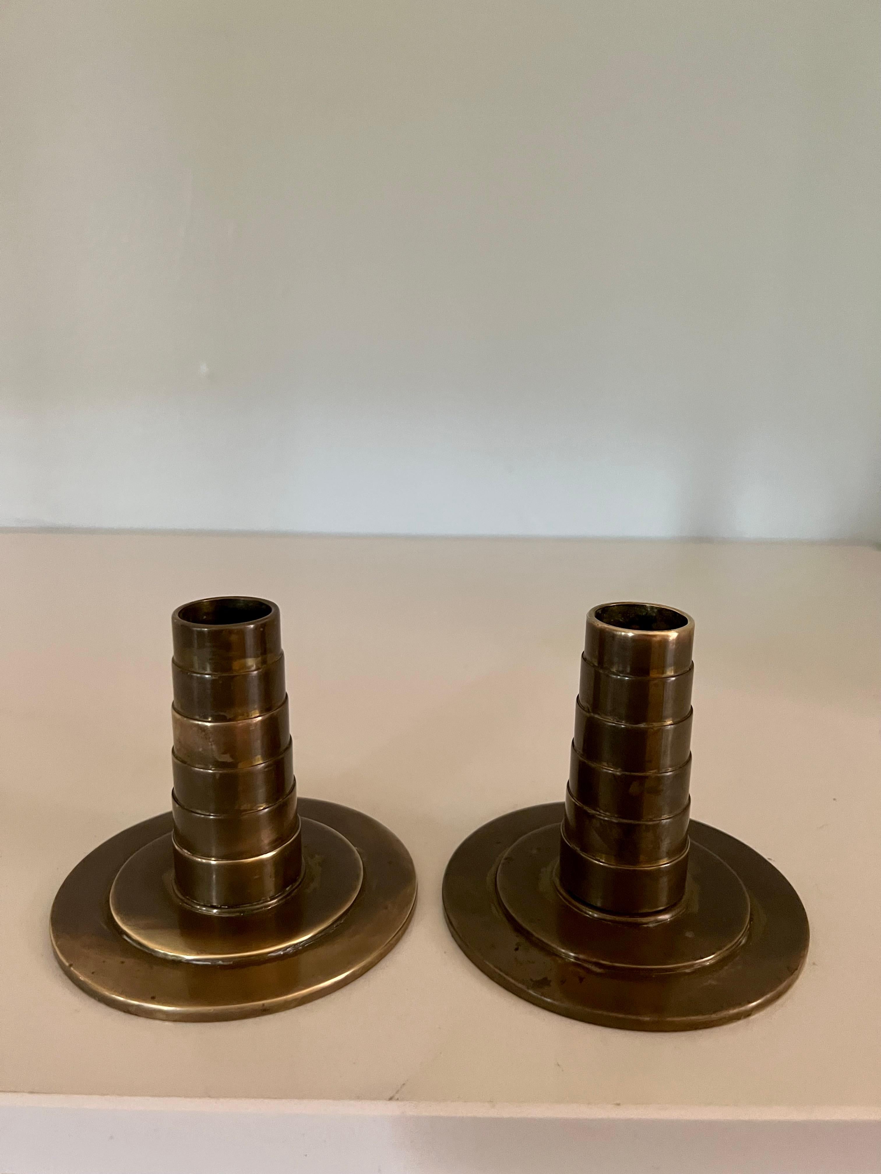 Pair of bronze candlestick holders. A compliment to many interiors, and especially those with an arts and crafts point of view. A solid addition to any table. Perfectly patinated and will catch candlelight wonderfully. 

