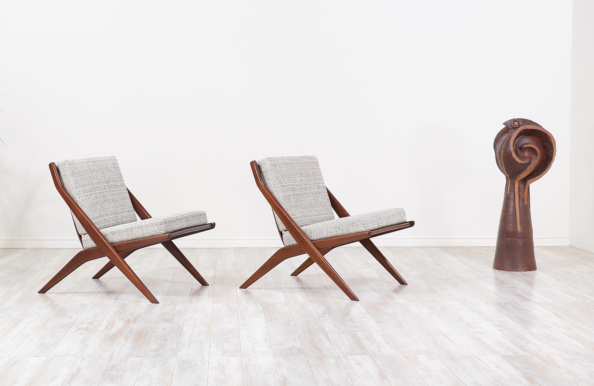 Pair of stylish modern lounge chairs designed in Sweden by Folke Ohlsson for DUX of Sweden circa 1950s. These Minimalist lounge chairs feature a scissor-like solid walnut-stained beechwood frame with new high-density foam cushions and light-colored