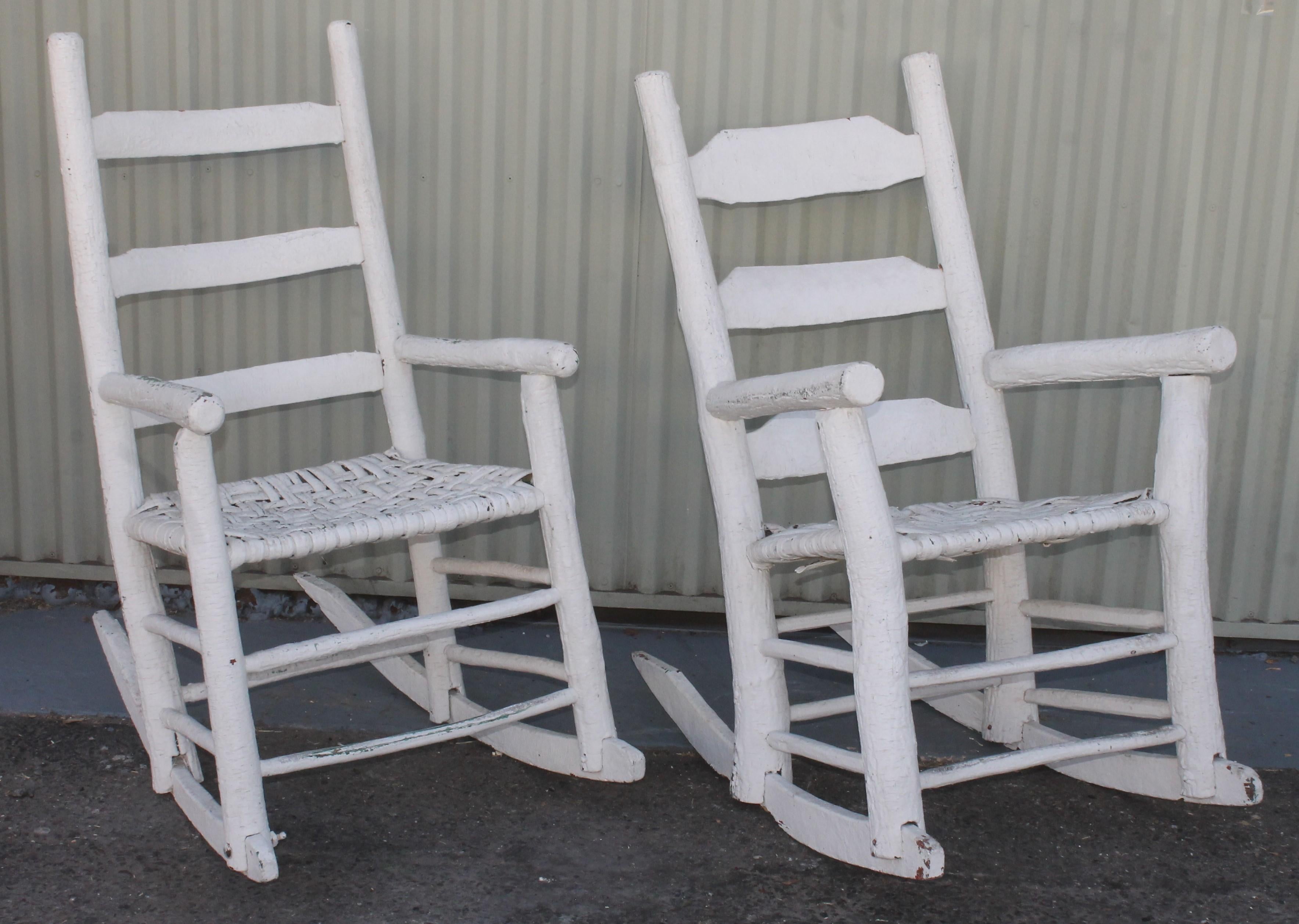 These handmade folky white painted ladder back rocking chairs have hand woven splint seats. The condition is good with wear to the base but both are very strong and sturdy.

shorter rocking chair measures 
33 depth x 22 width x 38 high ans 18