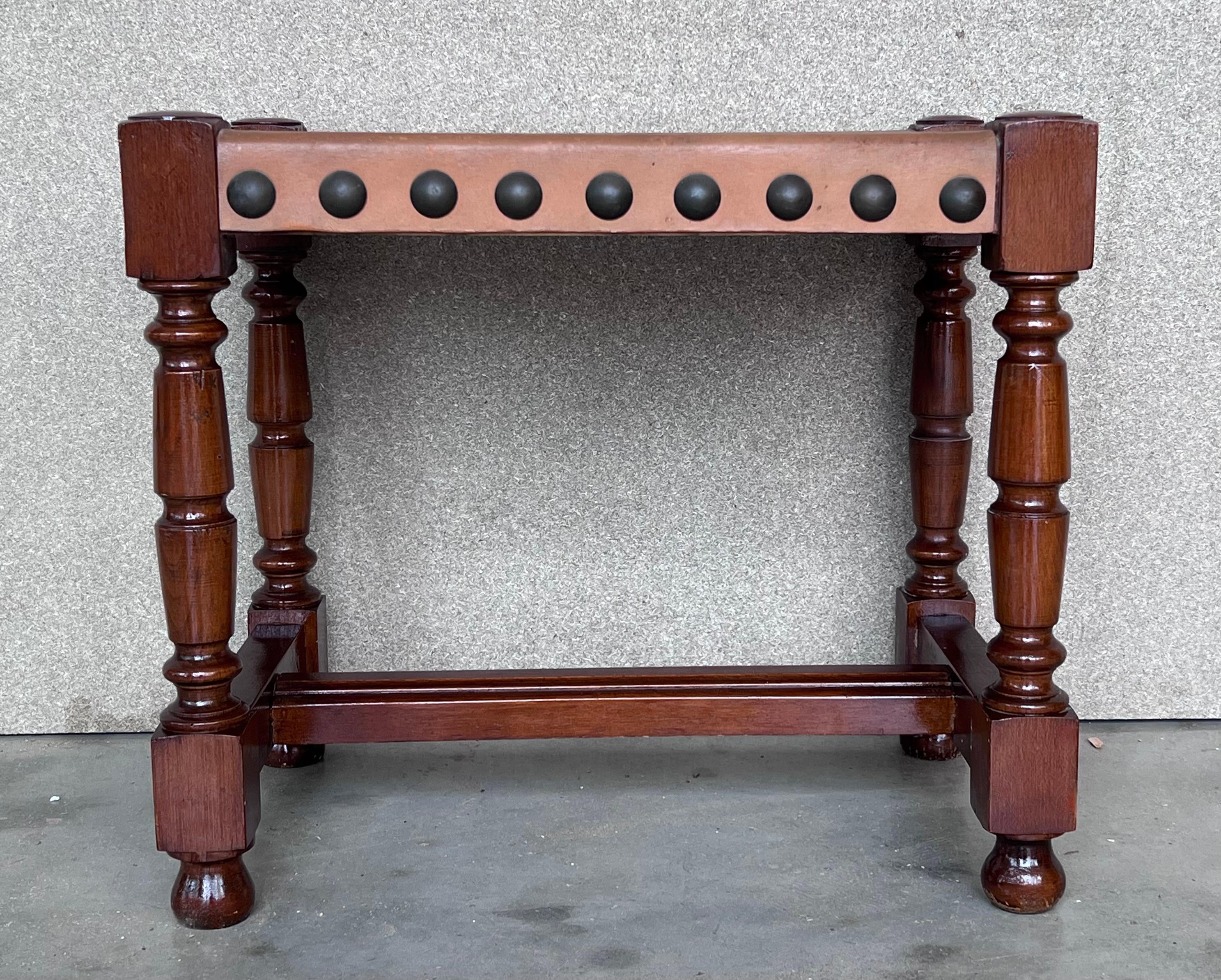 The structure forms a rectangular form with both sides of the base intersecting and supporting each other. The seats are natural cowhide and attached to the frame by large round bronze tacks, 20th century.