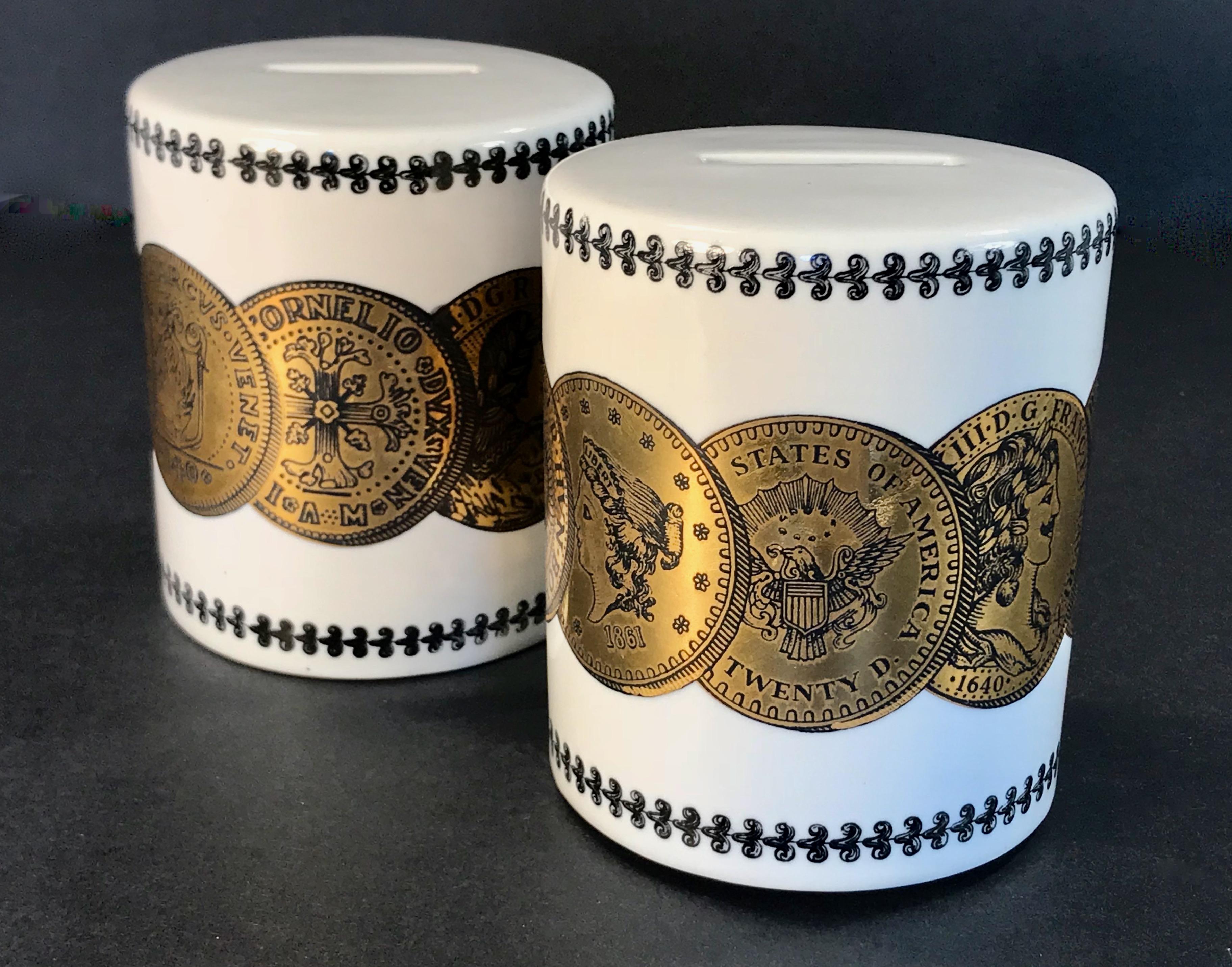 A pair of white porcelain coin or piggy banks designed by Piero Fornasetti for Neiman Marcus. Gilt coin motif with scrollwork detailing at top and bottom. These retain the original stoppers and we have added cork stoppers. Coin banks by Fornasetti