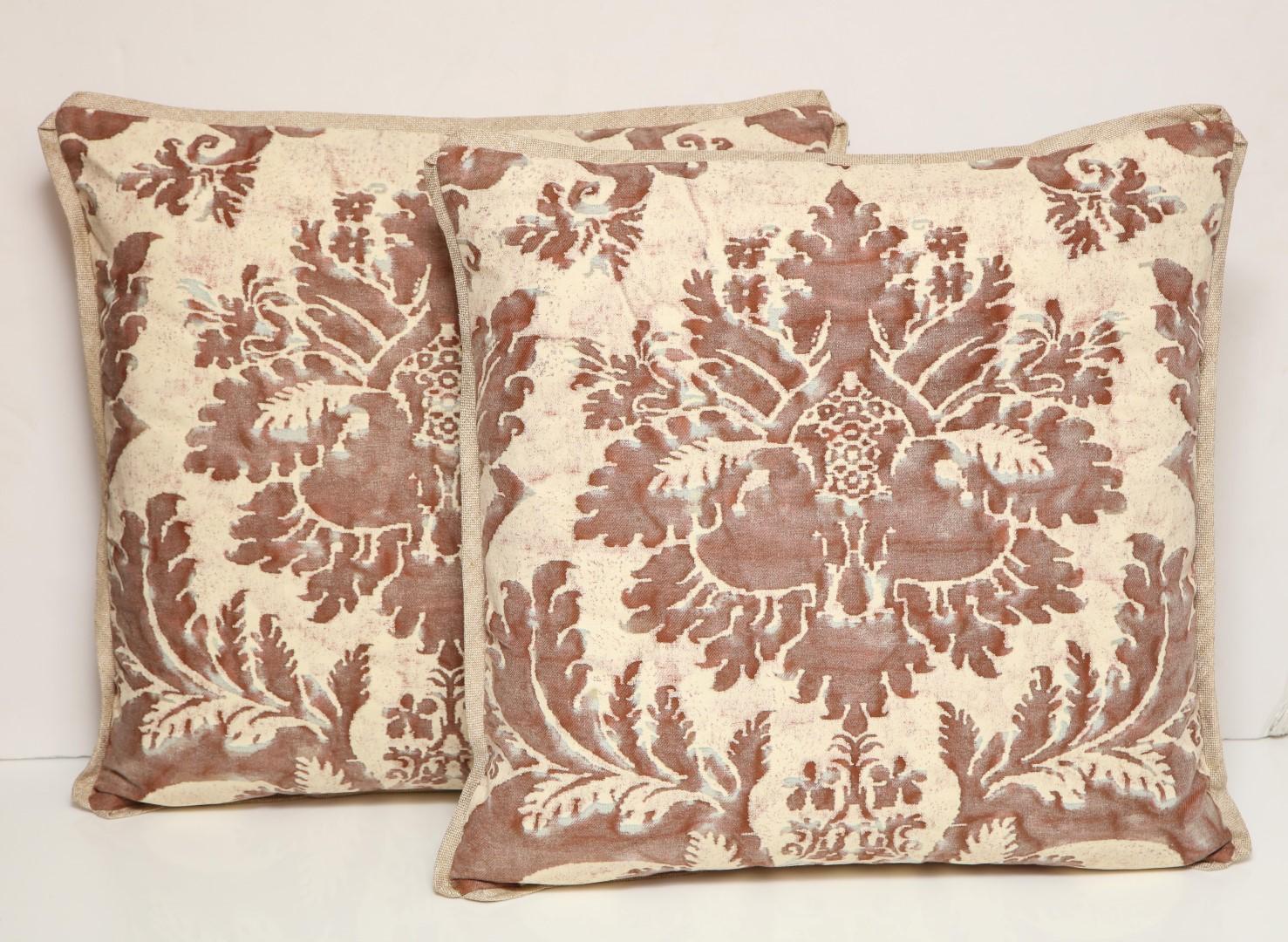 A pair of Fortuny fabric cushions in the Glicine pattern, caramel and white color way, cotton/linen blend backing material and striped silk bias edging, the pattern, 17th century Italian design with Wisteria motif. Newly made using vintage Fortuny