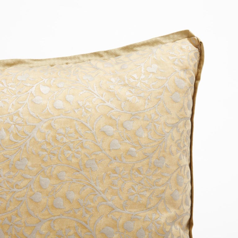 A pair of Fortuny fabric cushions in the Granada pattern, featuring a lovely gold and silvery gold colorway. The details of these cushions are exquisite: each cushion has silk bias edging and features a gold silk backing material. The pattern is a