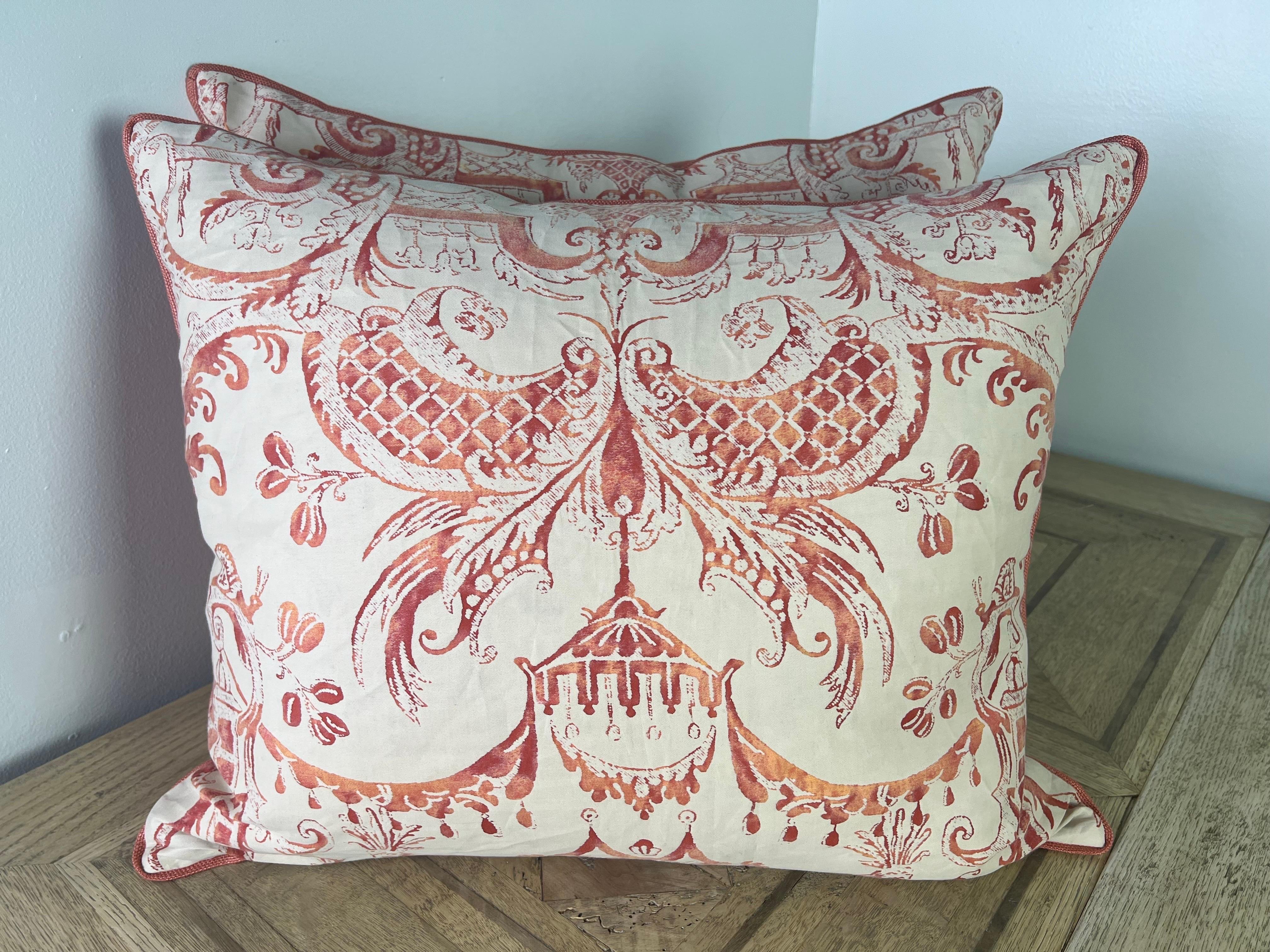 Pair of custom pillows with Fortuny's Mezzianno patterned Coral on ivory on the front and a solid coral linen on the backs. The pattern interpreted from designs of Jean Berain, depicting addorsed and confronting monkeys and lions set amidst